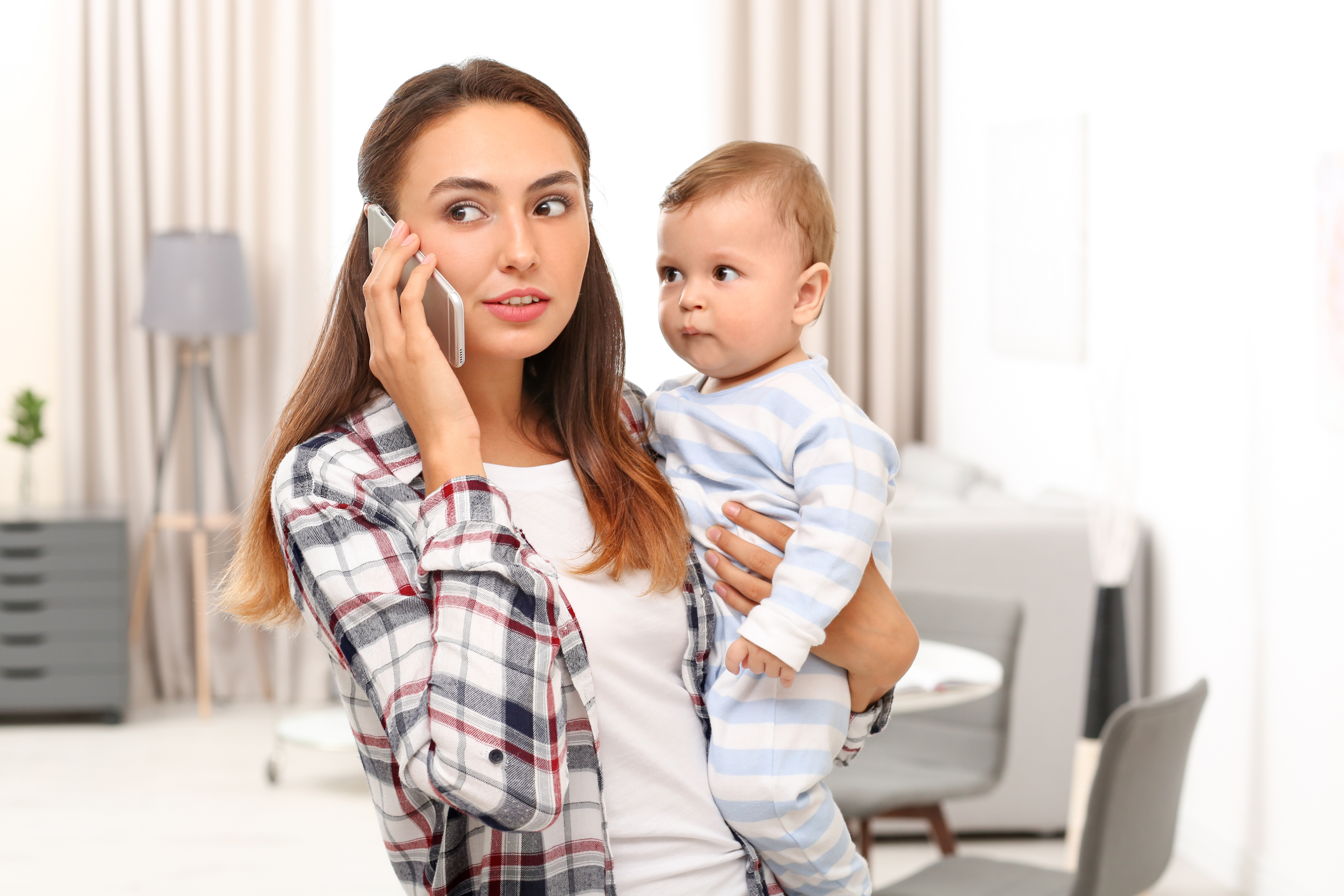 Madre con su bebé en brazos habla por teléfono | Foto: Shutterstock