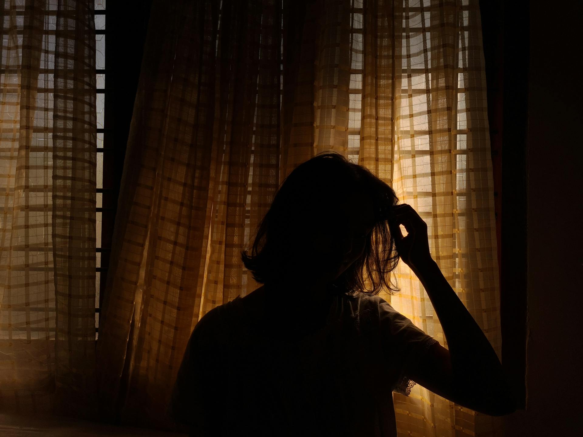 Silueta de una mujer junto a una ventana | Fuente: Pexels