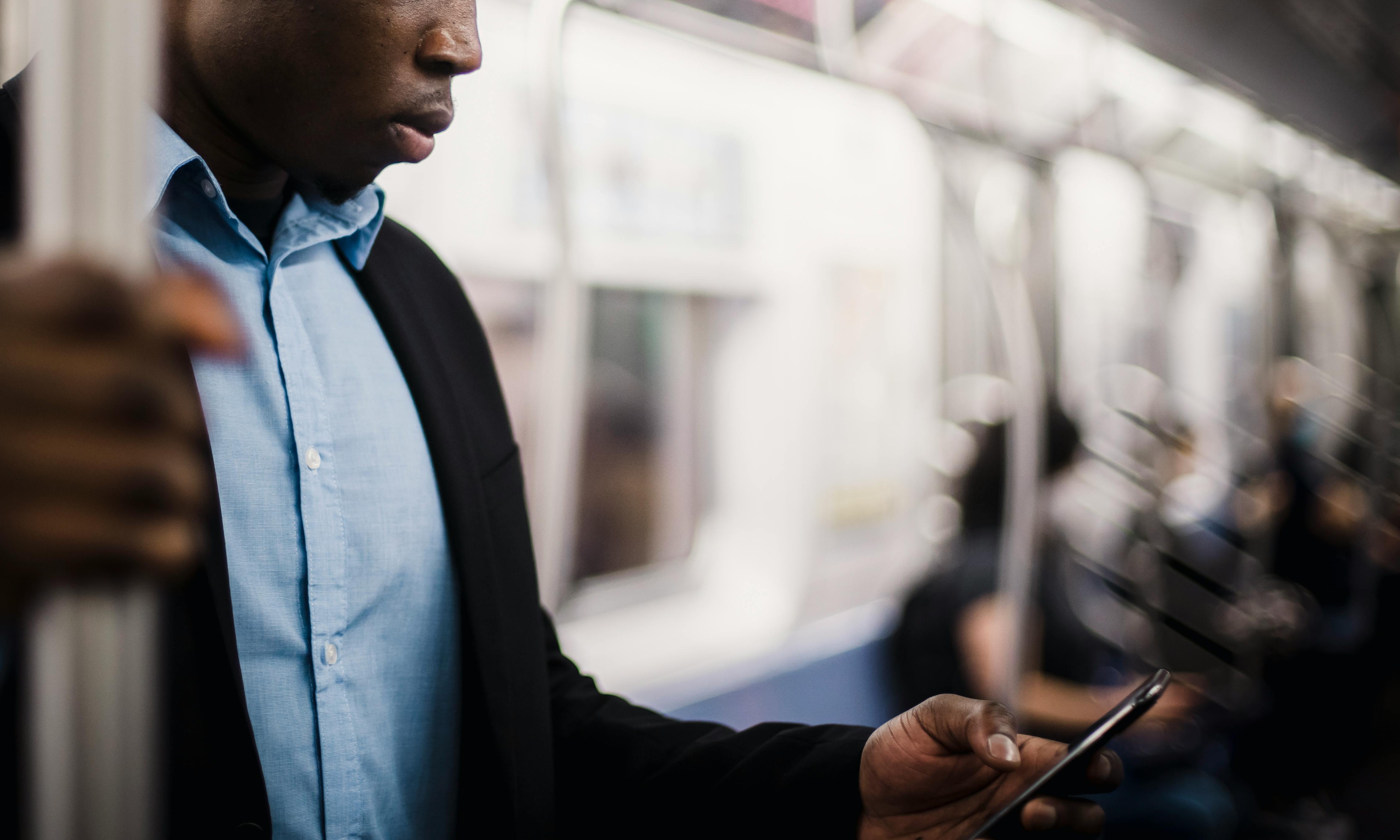 Un hombre trabaja con su móvil en un vagón de metro | Fuente: Pexels