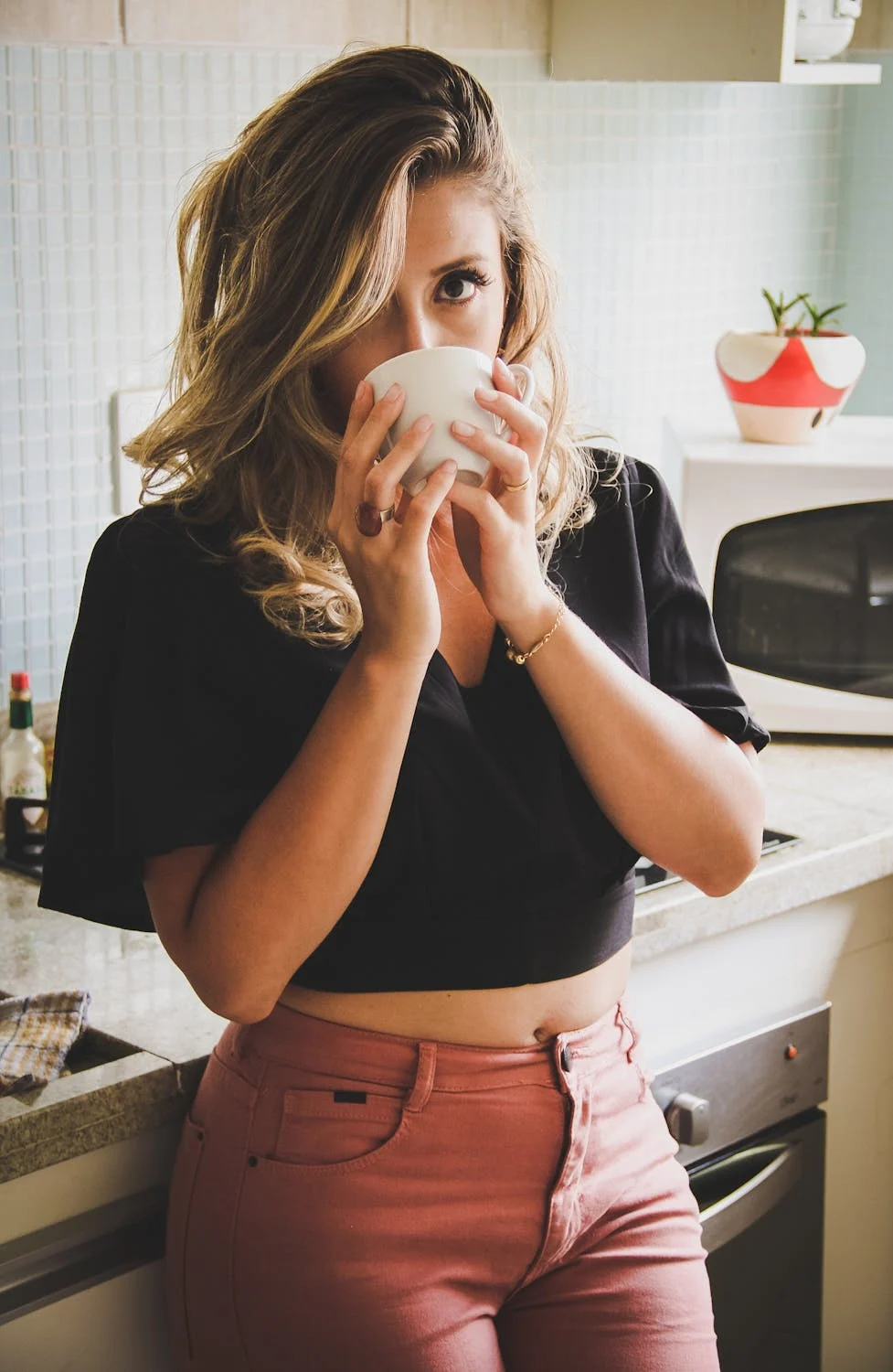 Una mujer tomando café en su cocina | Fuente: Pexels