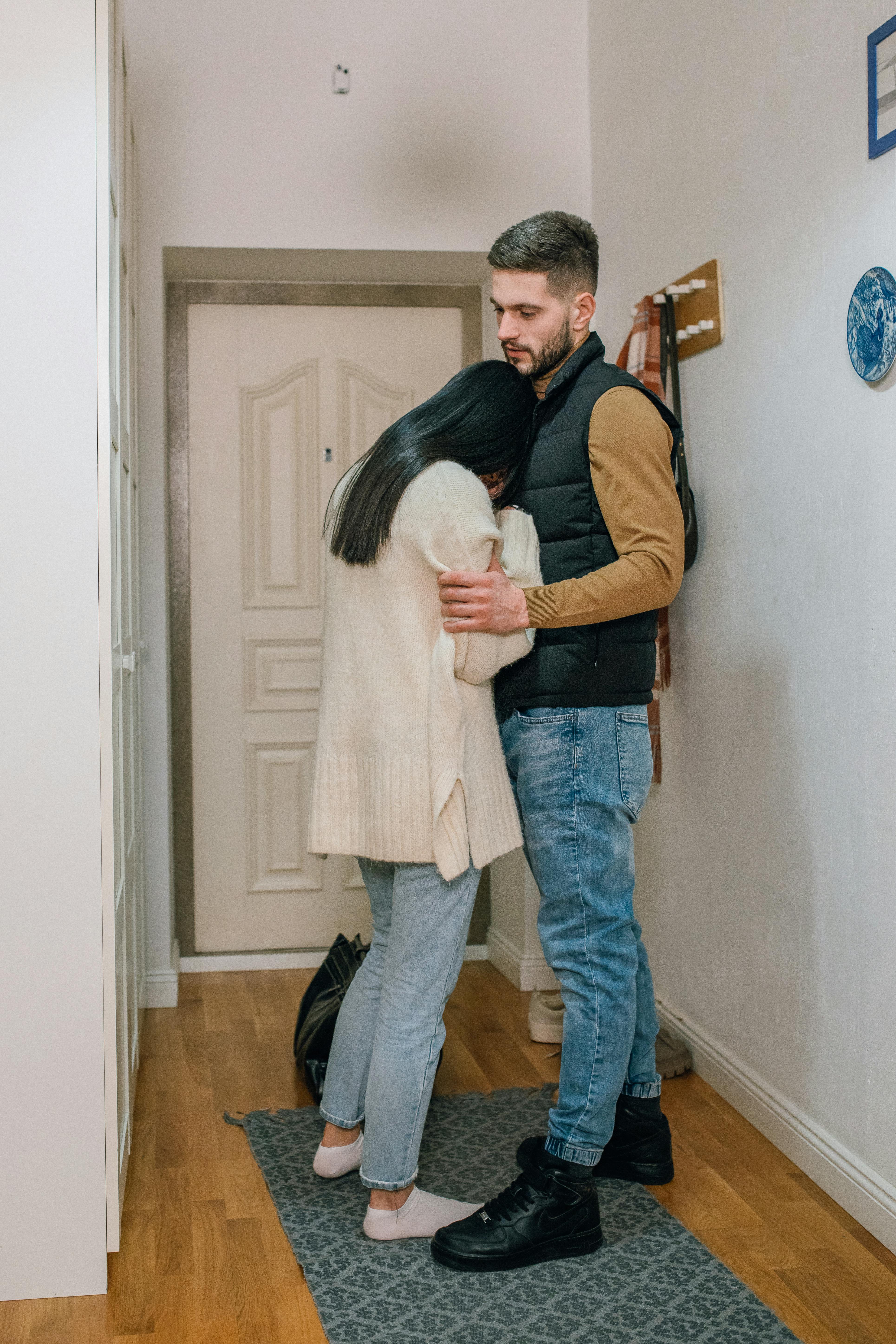 Un hombre parece impasible mientras una mujer llora en sus brazos | Foto: Pexels
