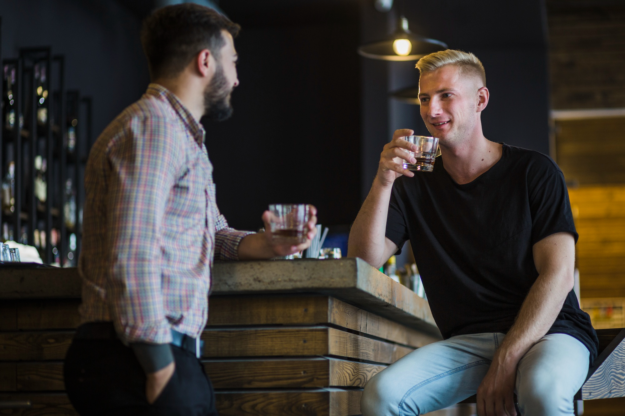 Dos amigos varones tomando unas copas por la noche en un bar | Fuente: Freepik