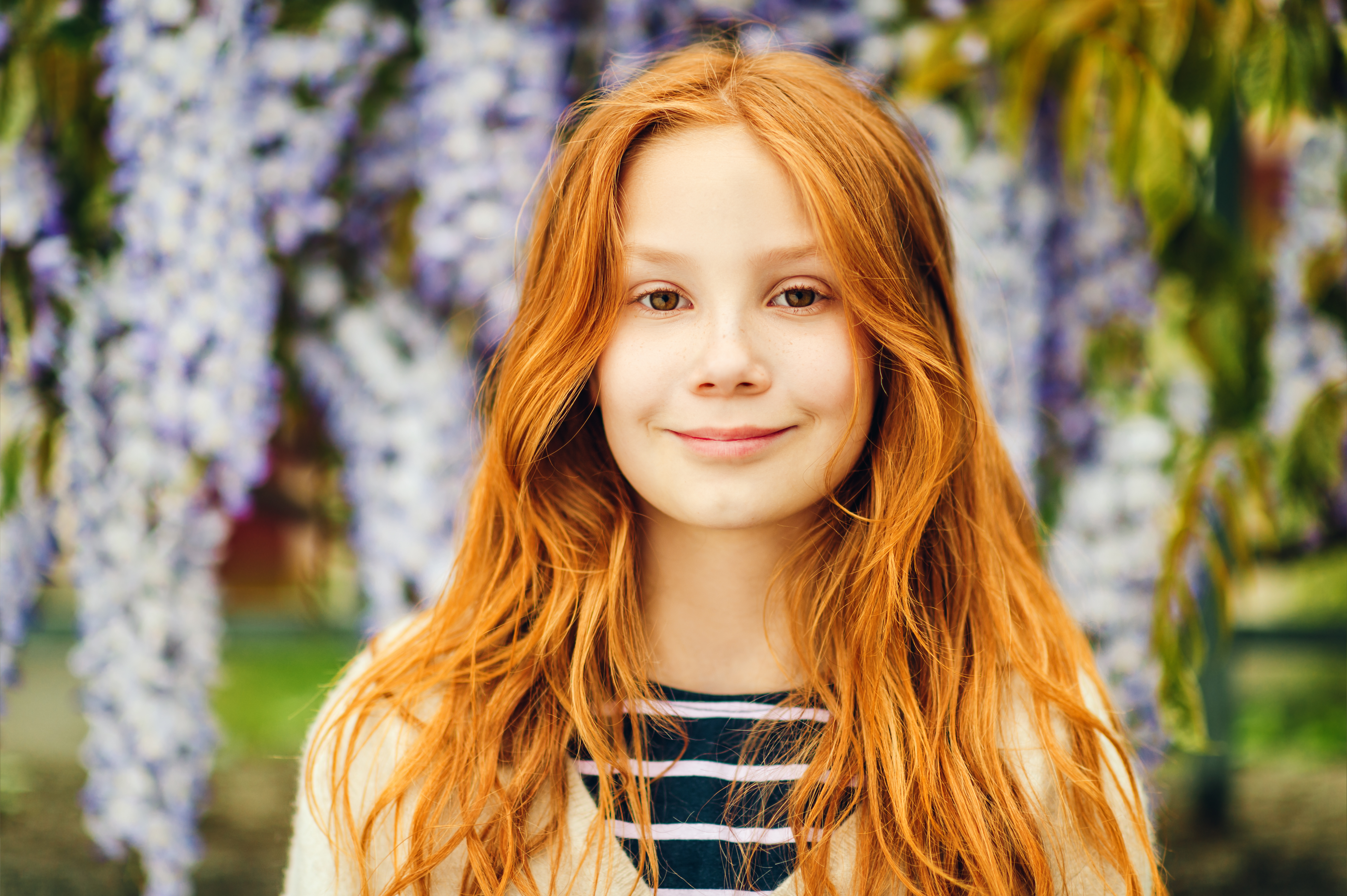 Una chica sonriendo delante de un árbol de glicinas. | Foto: Shutterstock
