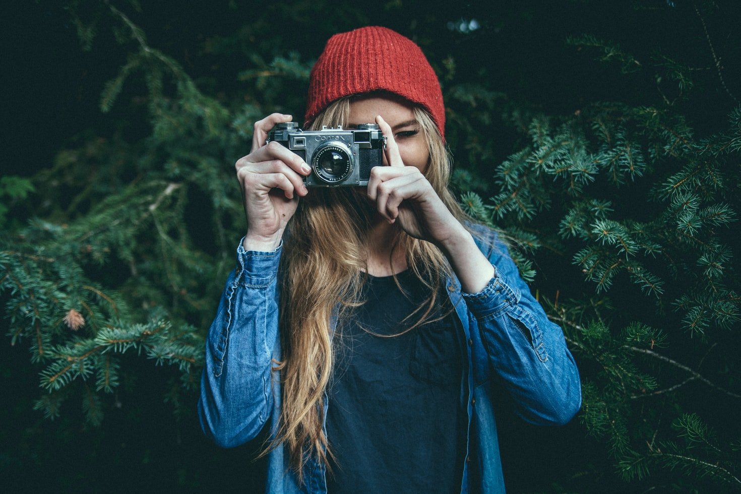 Una mujer joven utiliza su cámara para tomar una fotografía. | Foto: Unsplash