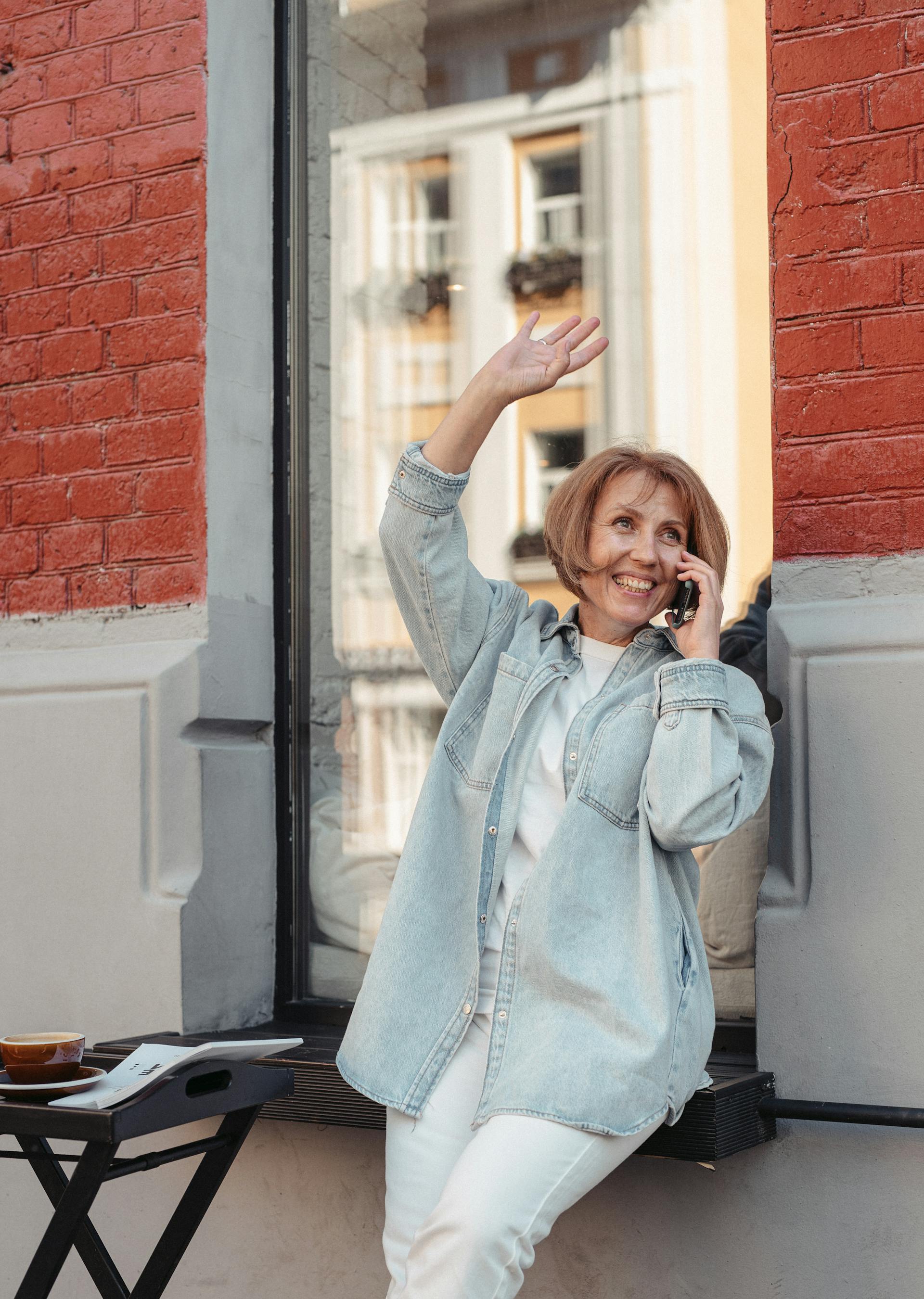 Una mujer sonriendo y saludando mientras atiende una llamada | Fuente: Pexels