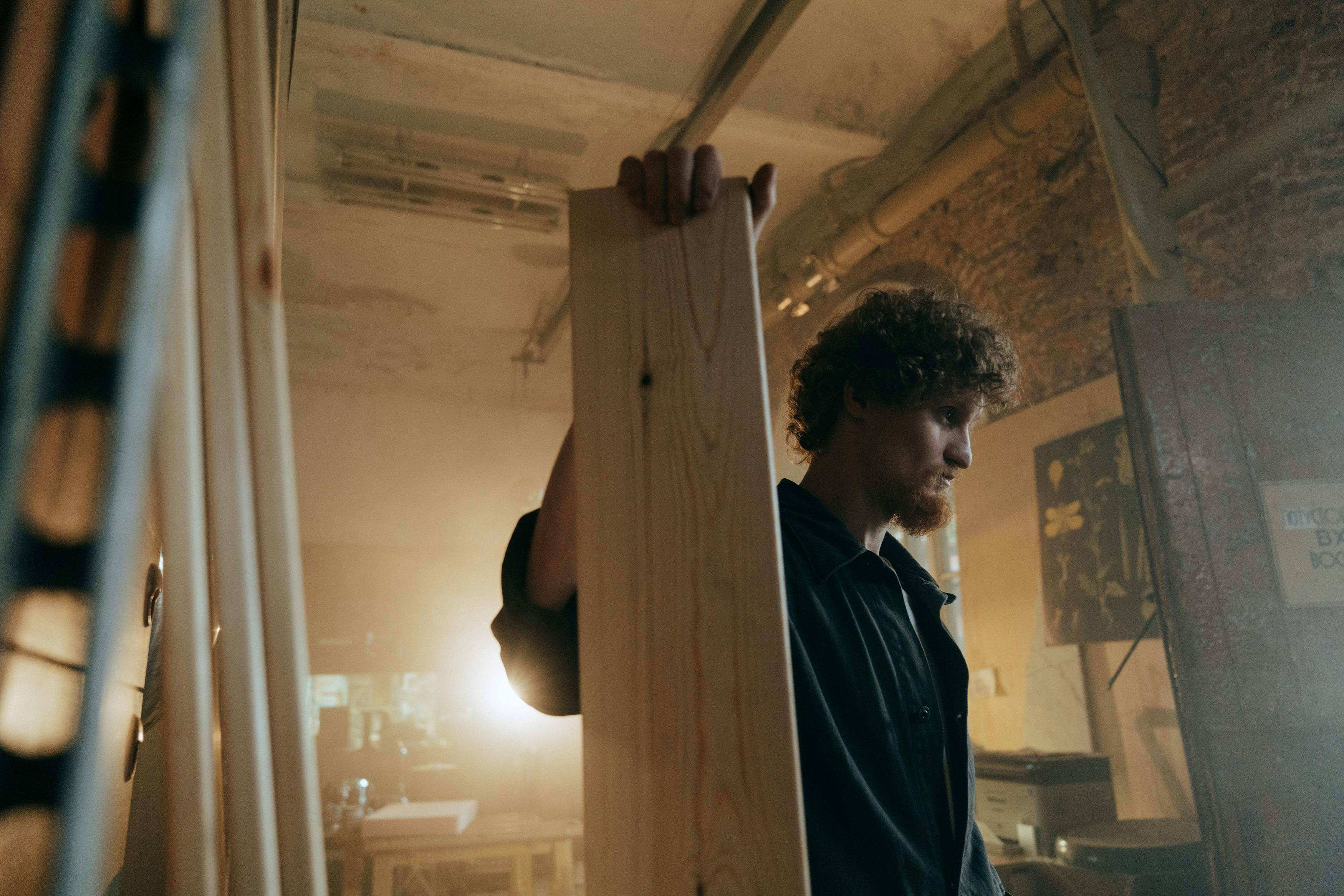 Un hombre sujetando un panel de madera | Fuente: Pexels