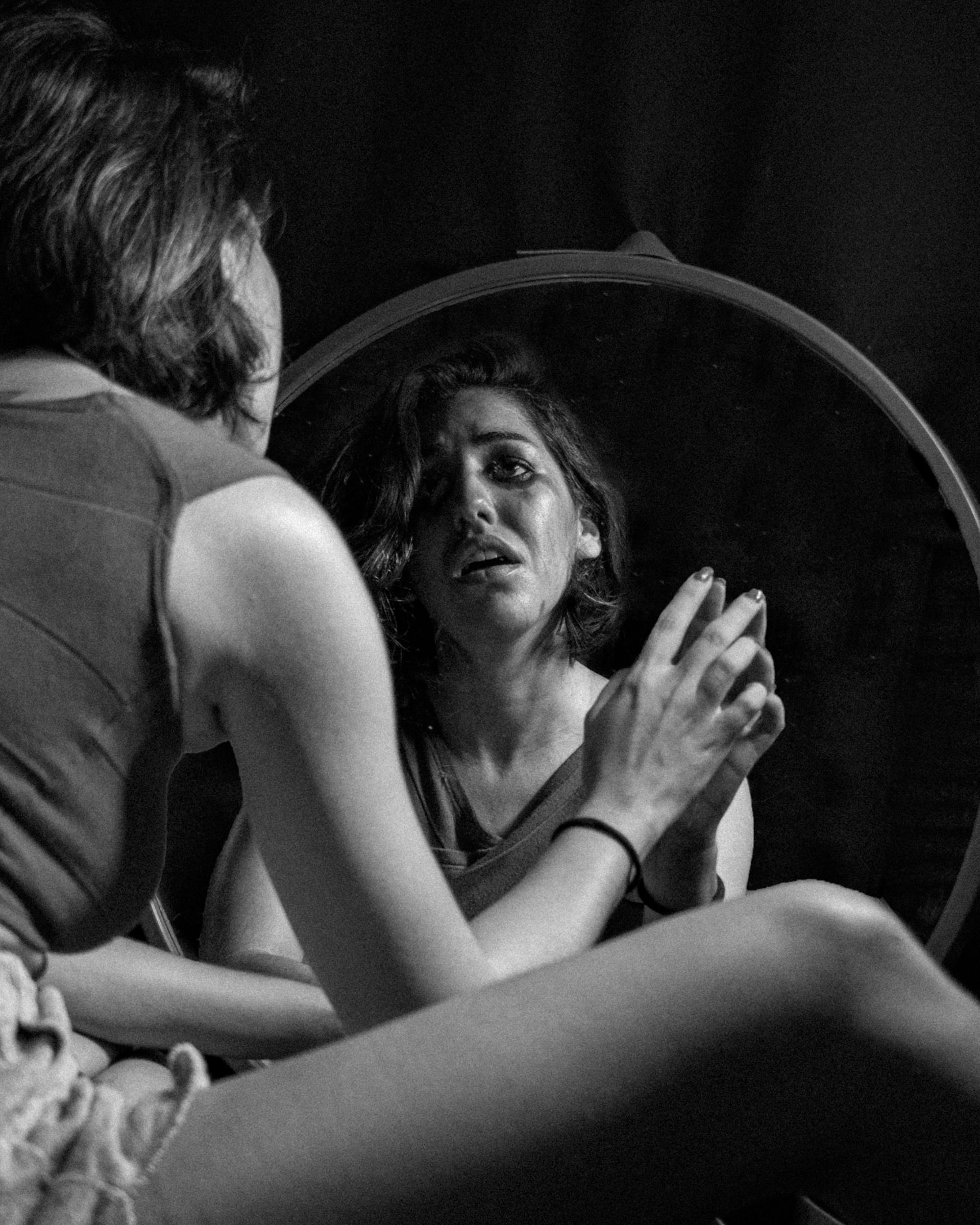 Foto en escala de grises de una mujer llorando mirándose al espejo | Fuente: Pexels