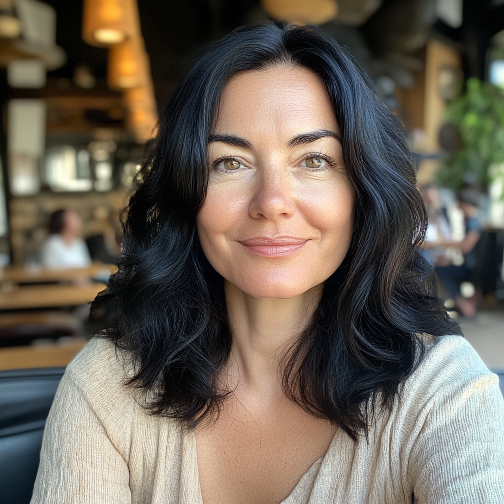 Una mujer sonriente sentada en una cafetería | Fuente: Midjourney