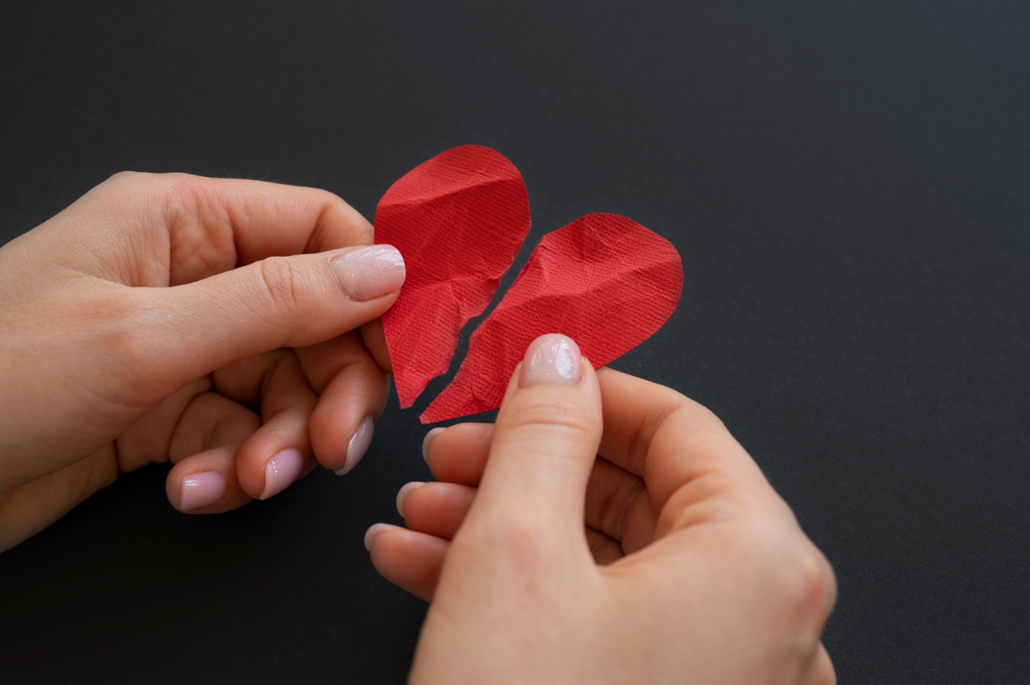 Una mujer con un corazón de papel roto | Fuente: Freepik