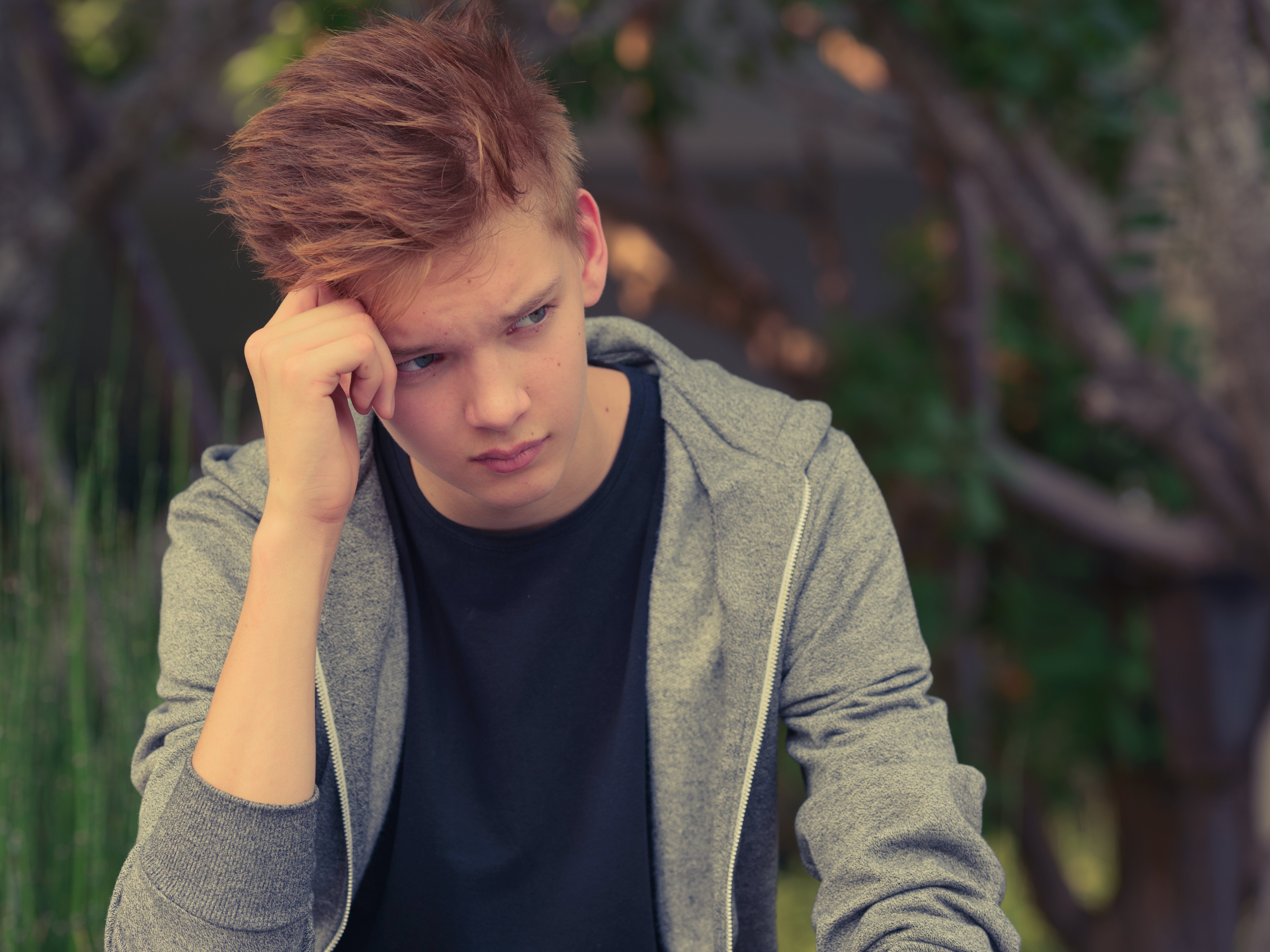 Un adolescente alterado sentado con la mano contra la cabeza | Foto: Shutterstock
