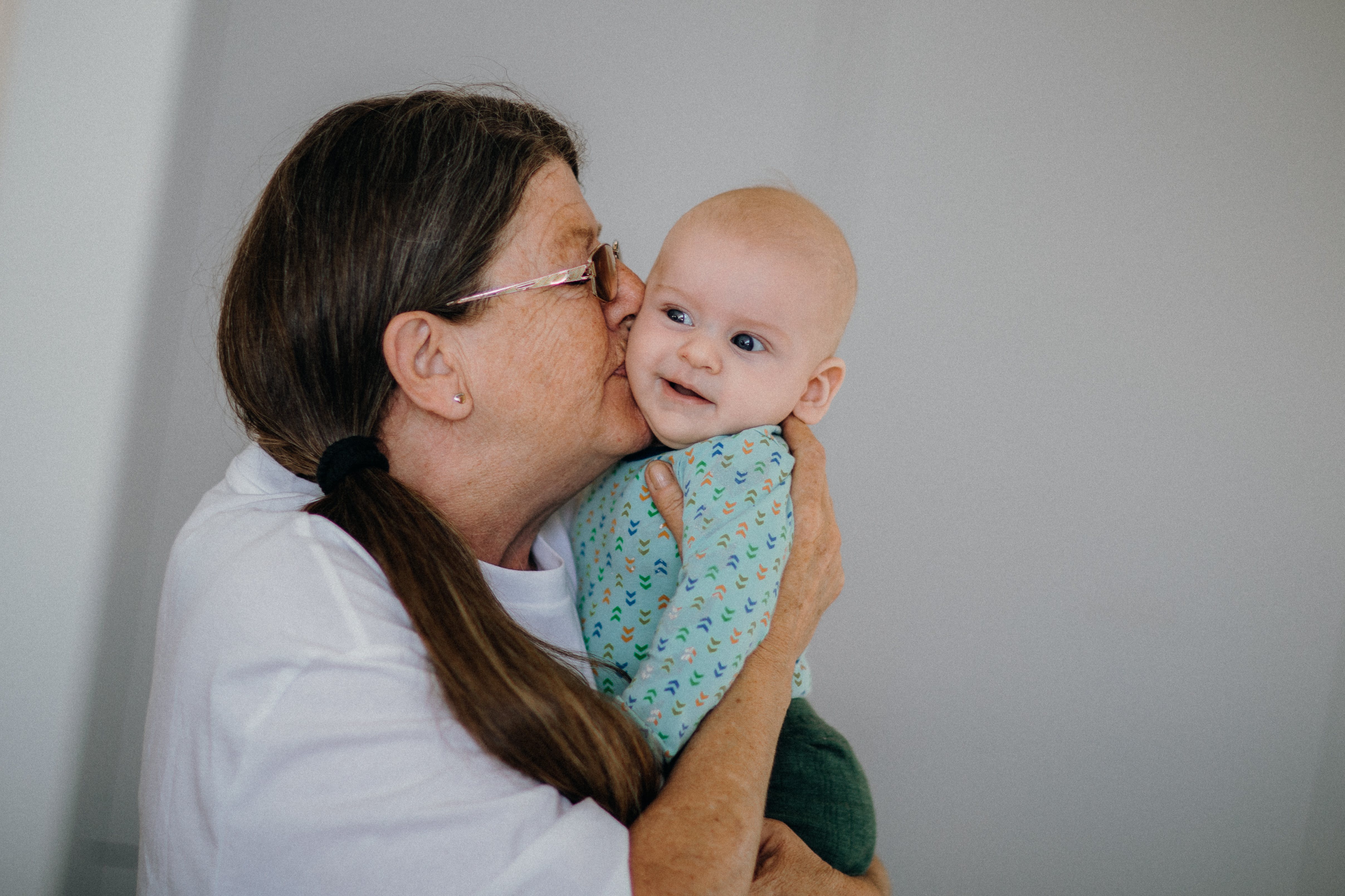 Una mujer mayor acuna y besa en la mejilla a un bebé | Foto: Pexels