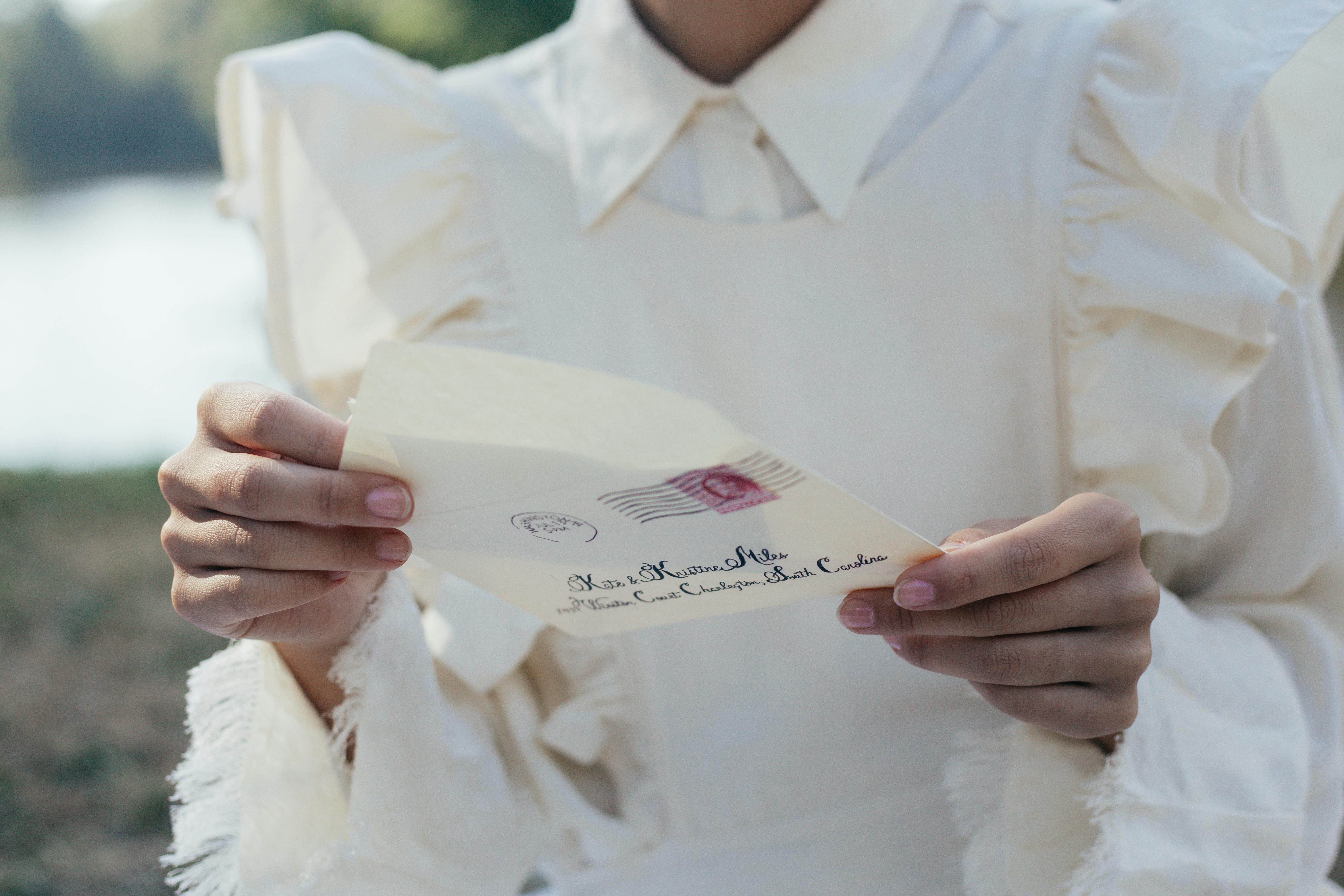 Persona vestida de blanco con una carta en la mano | Foto: Pexels