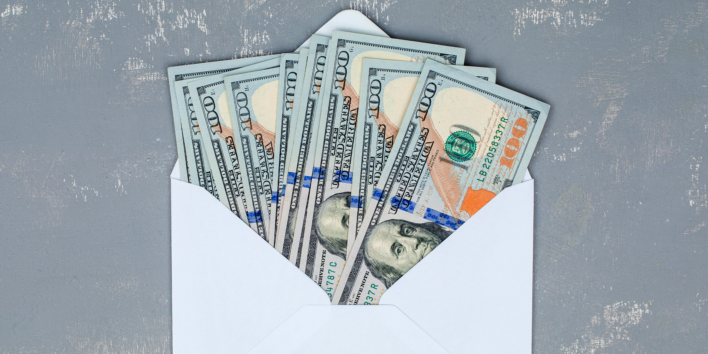 Un sobre blanco abierto lleno de billetes de 100 dólares | Fuente: Shutterstock