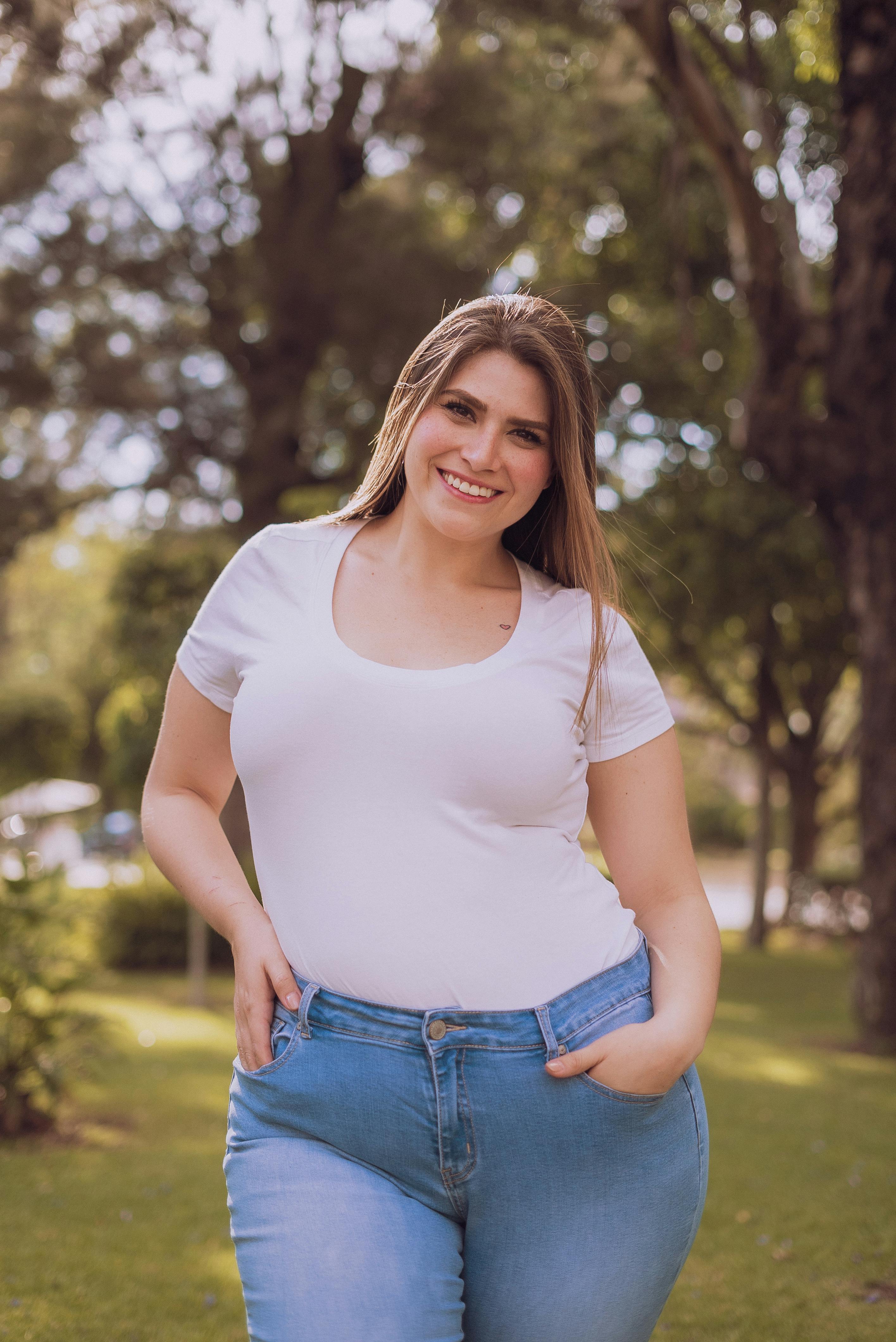 Una mujer sonriente con un top blanco y vaqueros | Fuente: Pexels