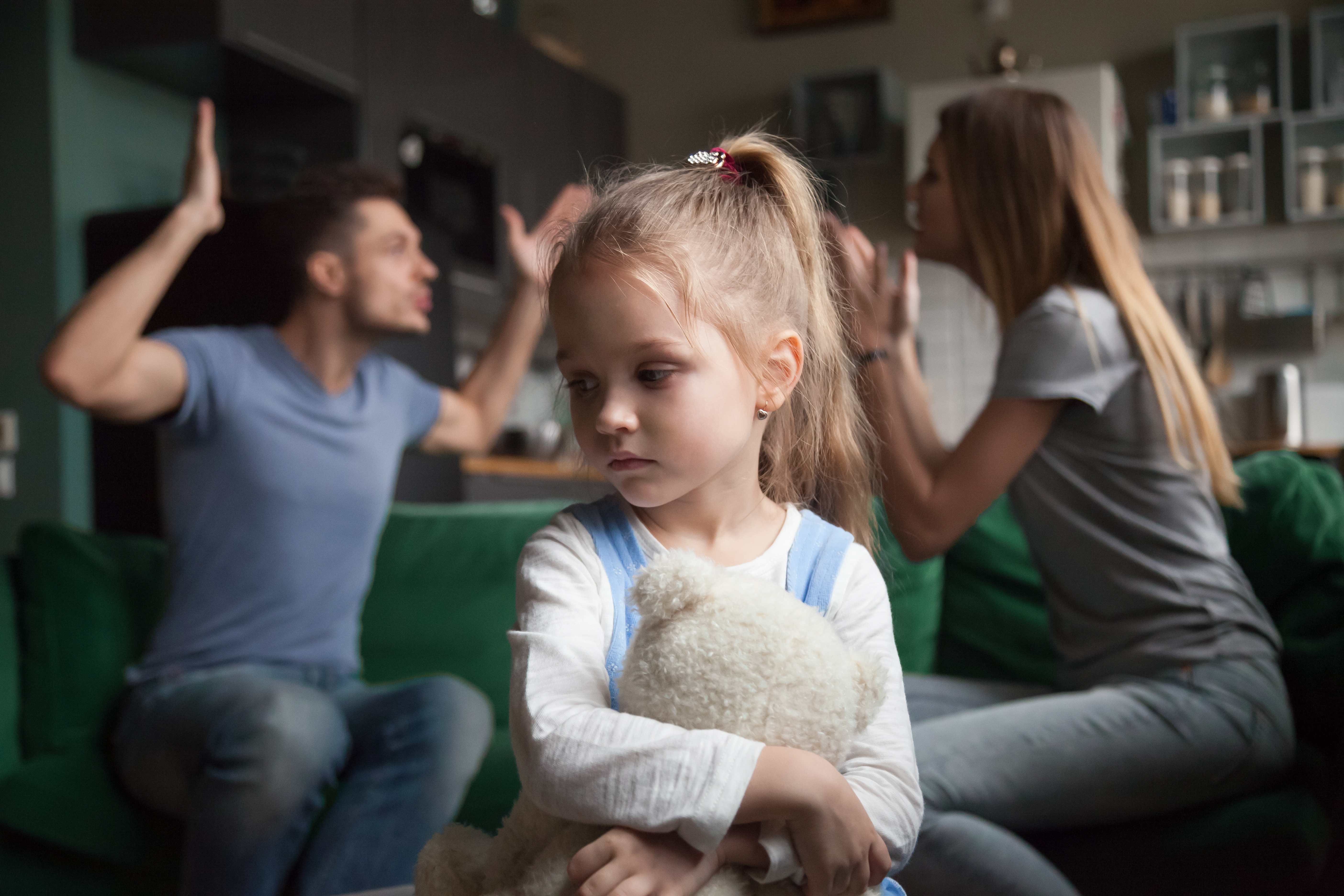 Una niña disgustada mientras sus padres discuten de fondo | Foto: Shutterstock