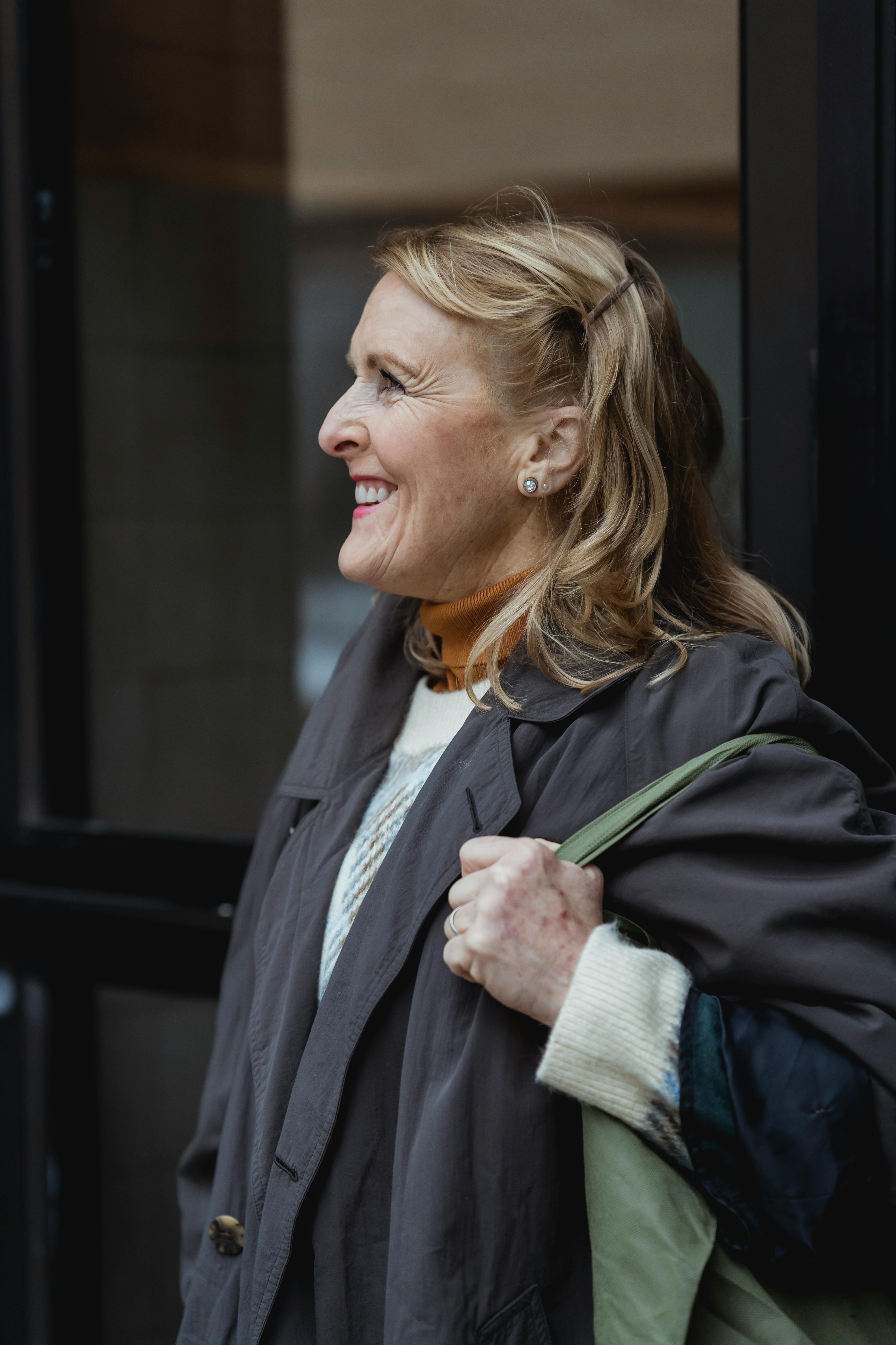 Una mujer feliz con una bolsa en la mano | Fuente: Pexels