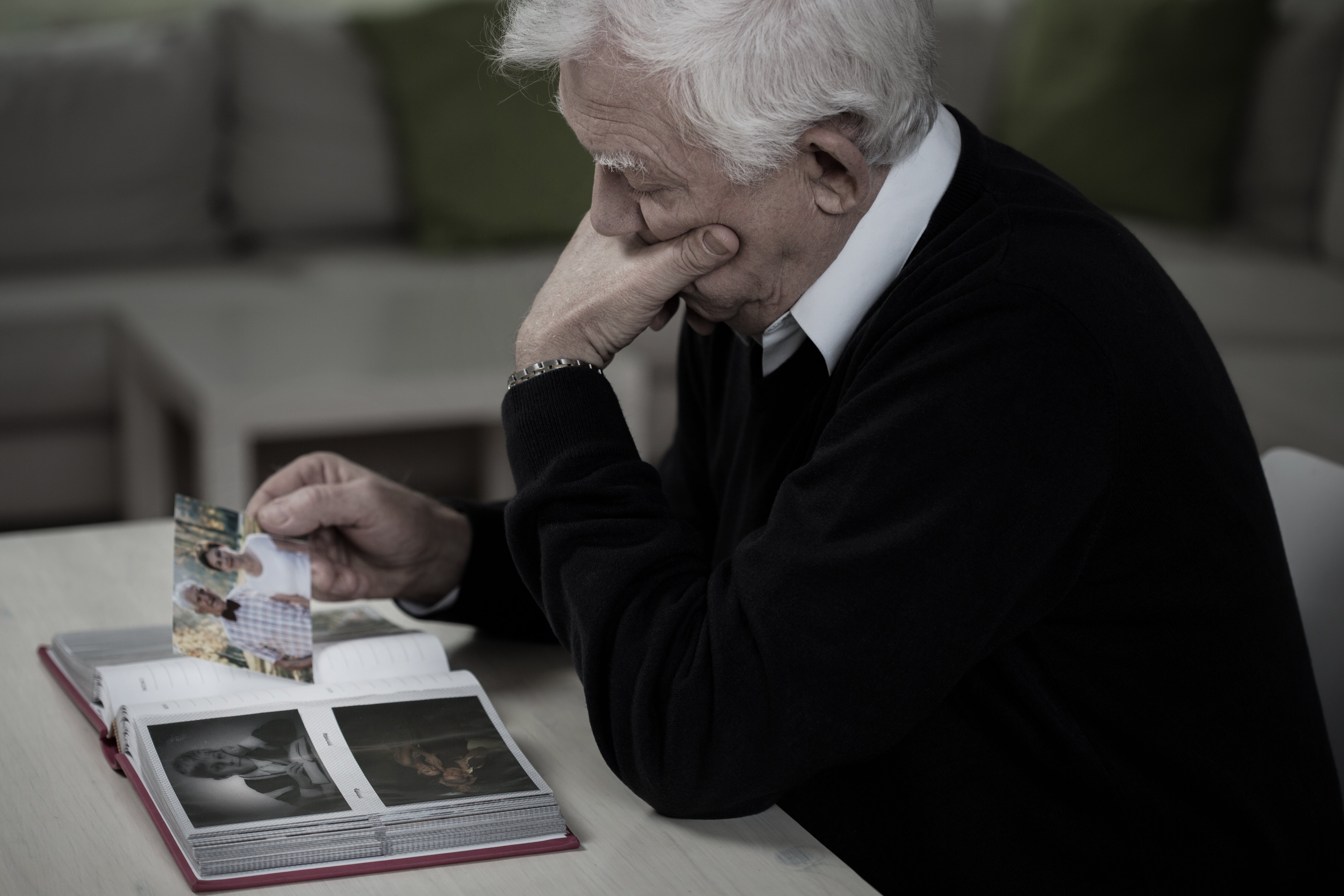 Hombre mayor viendo viejas fotos familiares. | Foto: Shutterstock