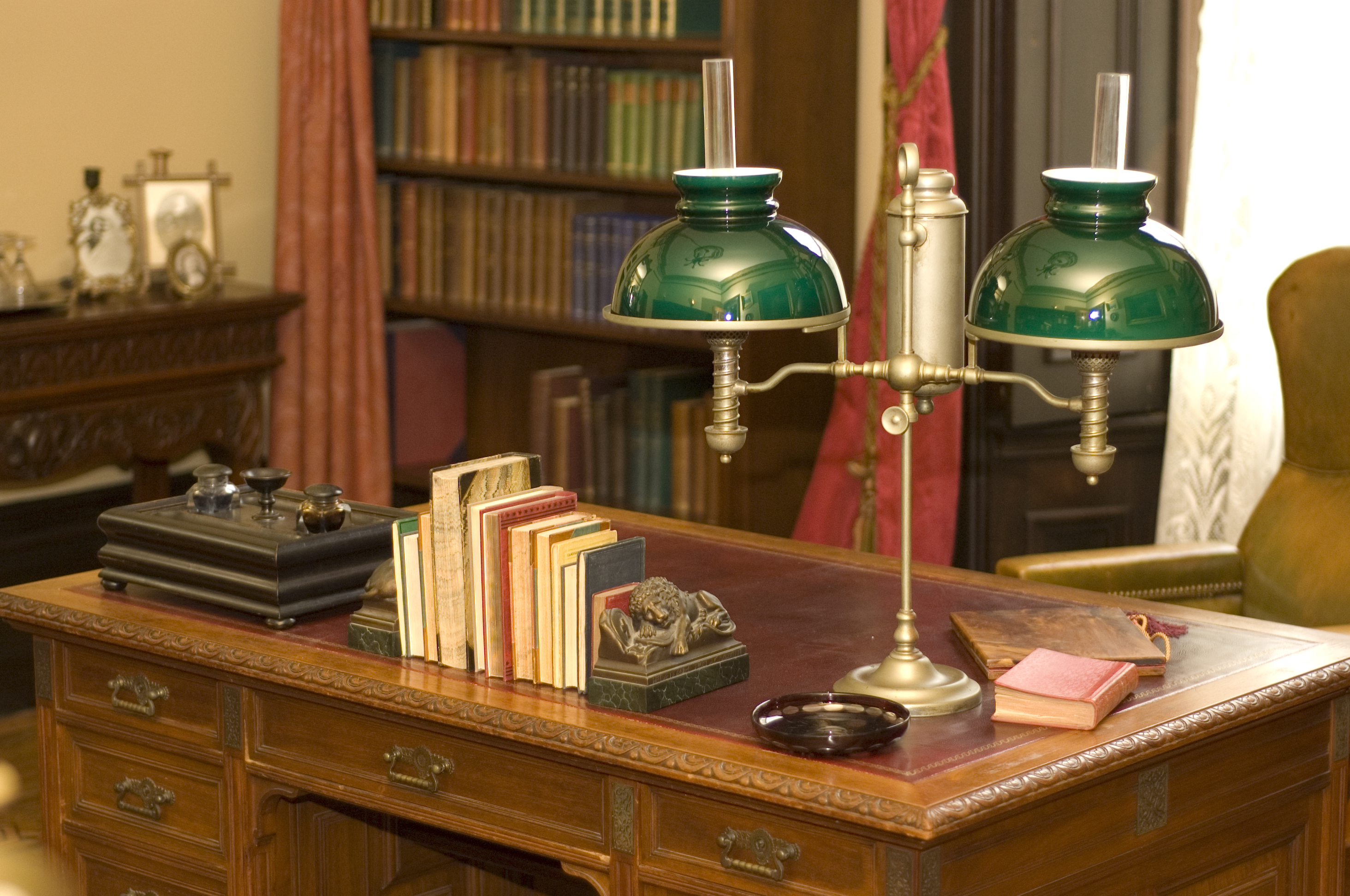 Una lámpara de aceite clásica y libros colocados sobre una antigua mesa de despacho | Fuente: Shutterstock