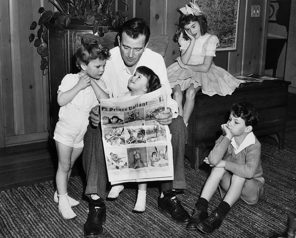 John Wayne leyendo un cómic de "Prince Valiant" con sus hijos Patrick, Melinda, Toni y Michael en Hollywood, California, en 1942. | Foto: Getty Images