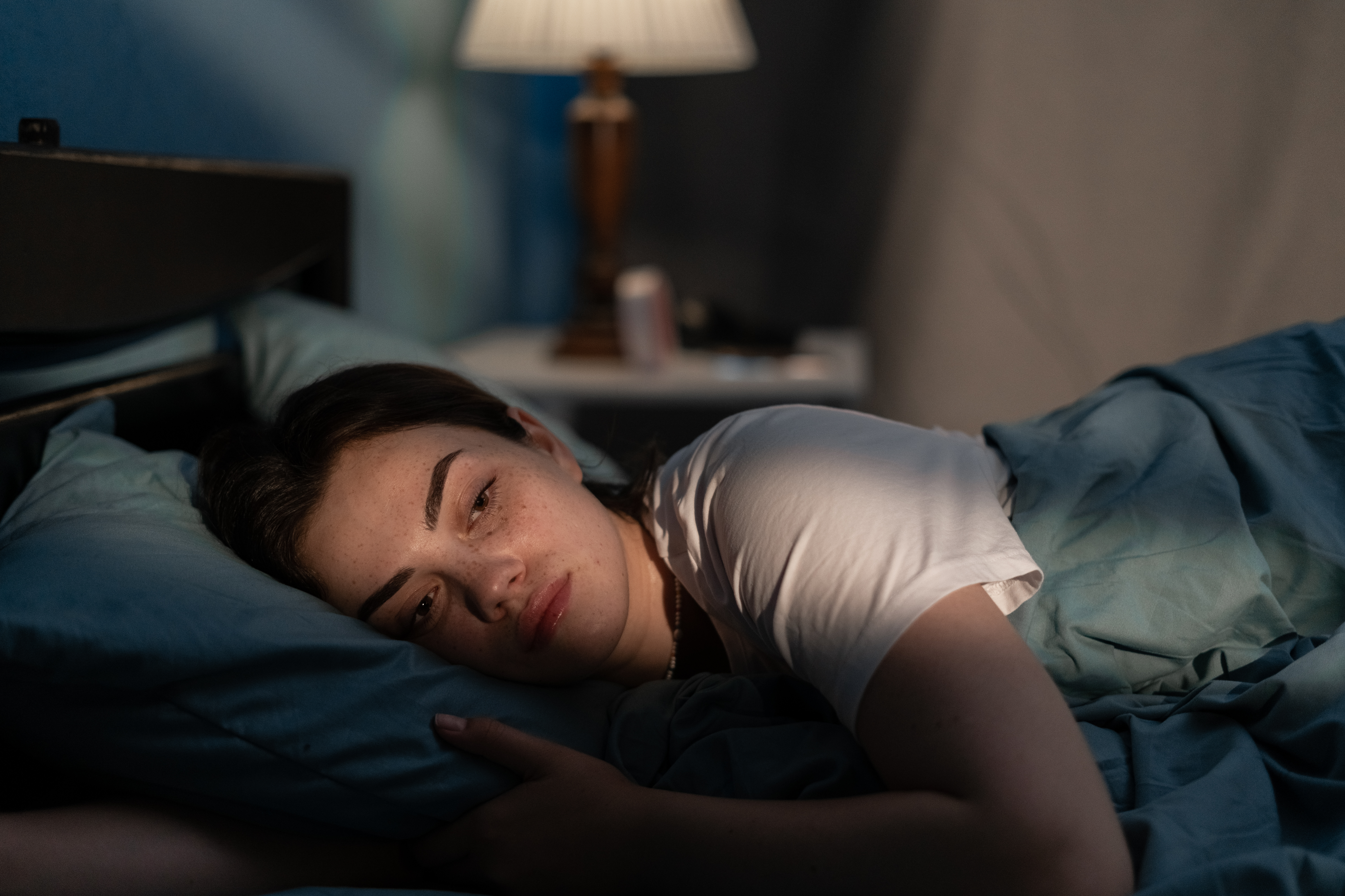 Mujer joven y triste tumbada en la cama a altas horas de la noche intentando dormir sufriendo insomnio | Foto: Getty Images