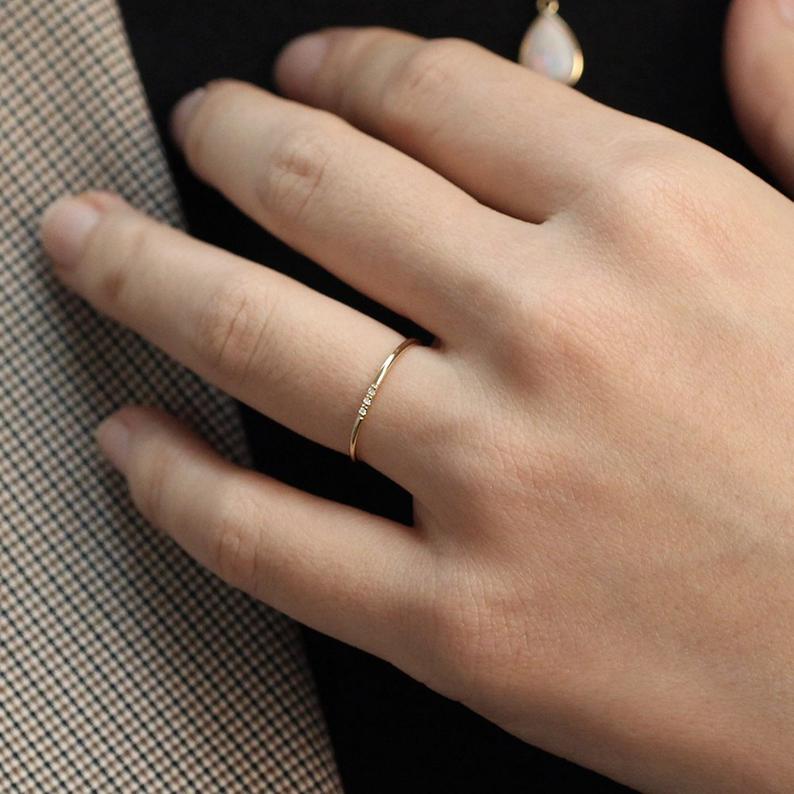 Alianza de boda minimalista de JSVConcepts Fine Jewelry in Gold con uno de tres diamantes. | Fuente: Etsy.com