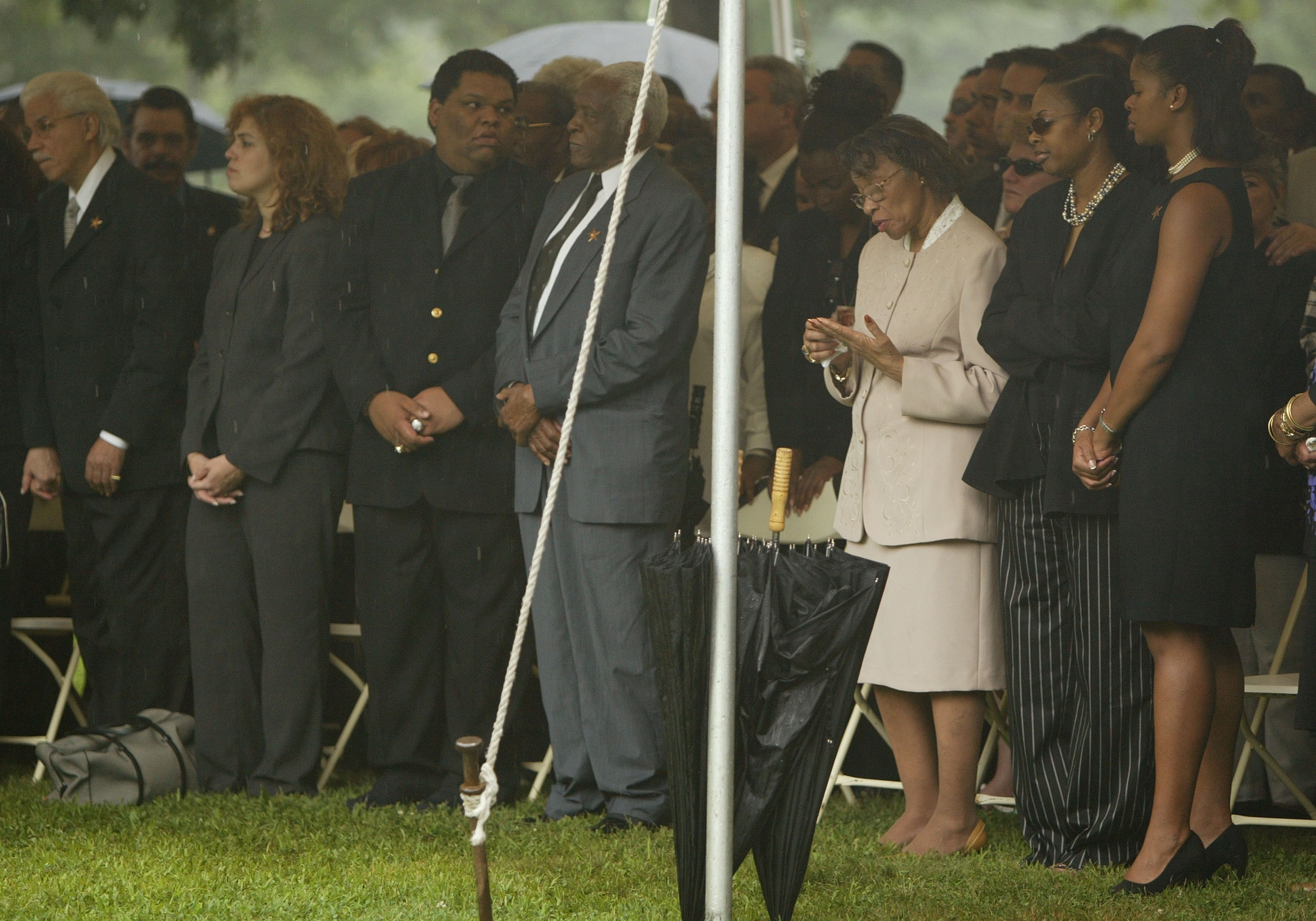 Pedro Knight, viudo de Celia Cruz, de pie junto a Gladys Bécquer (centro der.), hermana de Celia Cruz, en un tributo público en el Cementerio Woodlawn en julio de 2003 en el Bronx, Nueva York || Fuente: Getty Images