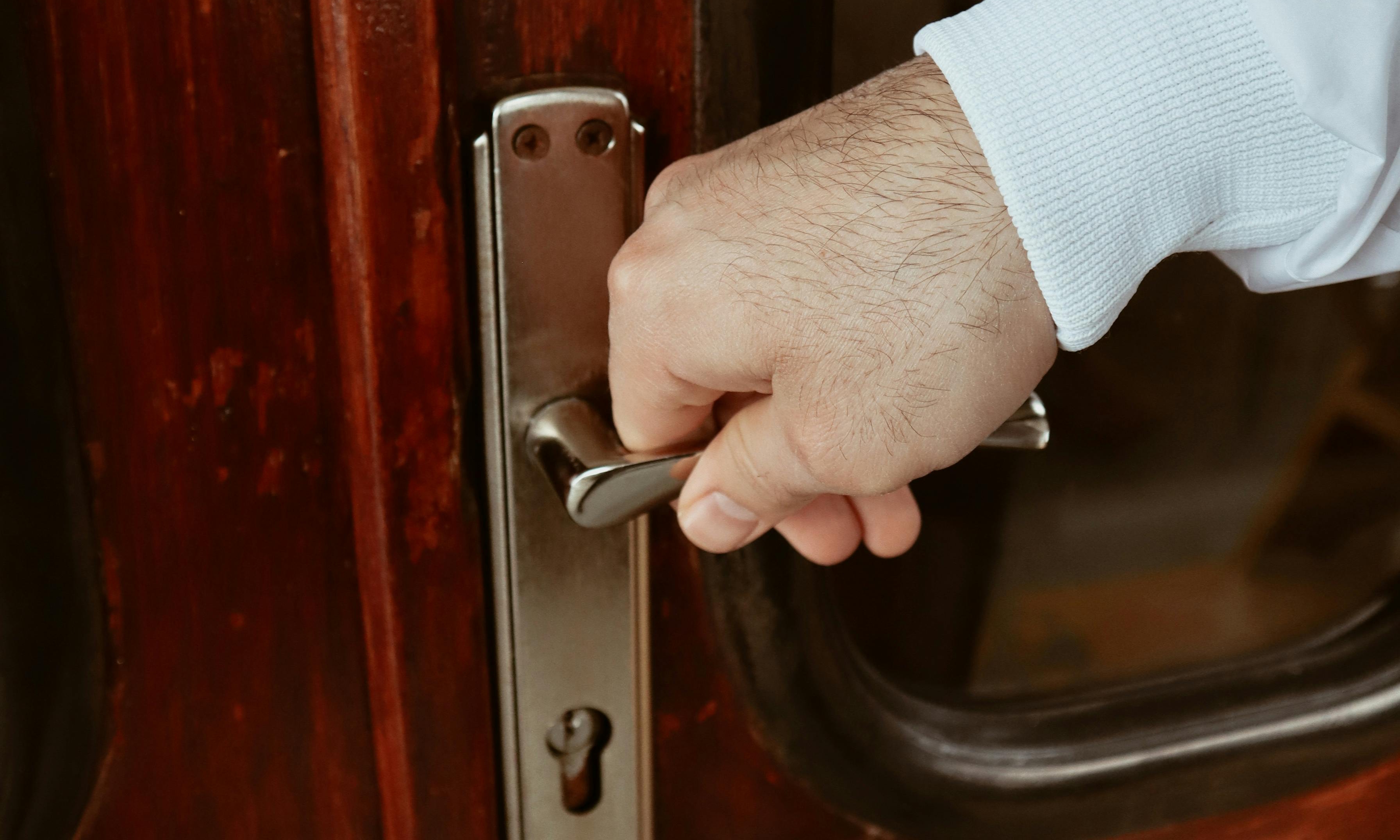 Primer plano de una mano agarrando la manilla de una puerta | Fuente: Pexels
