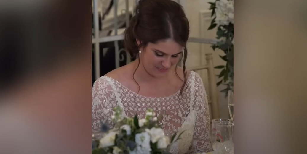 Katie sonríe mientras mira hacia abajo durante el discurso de boda de su marido | Fuente: YouTube / Daily Record