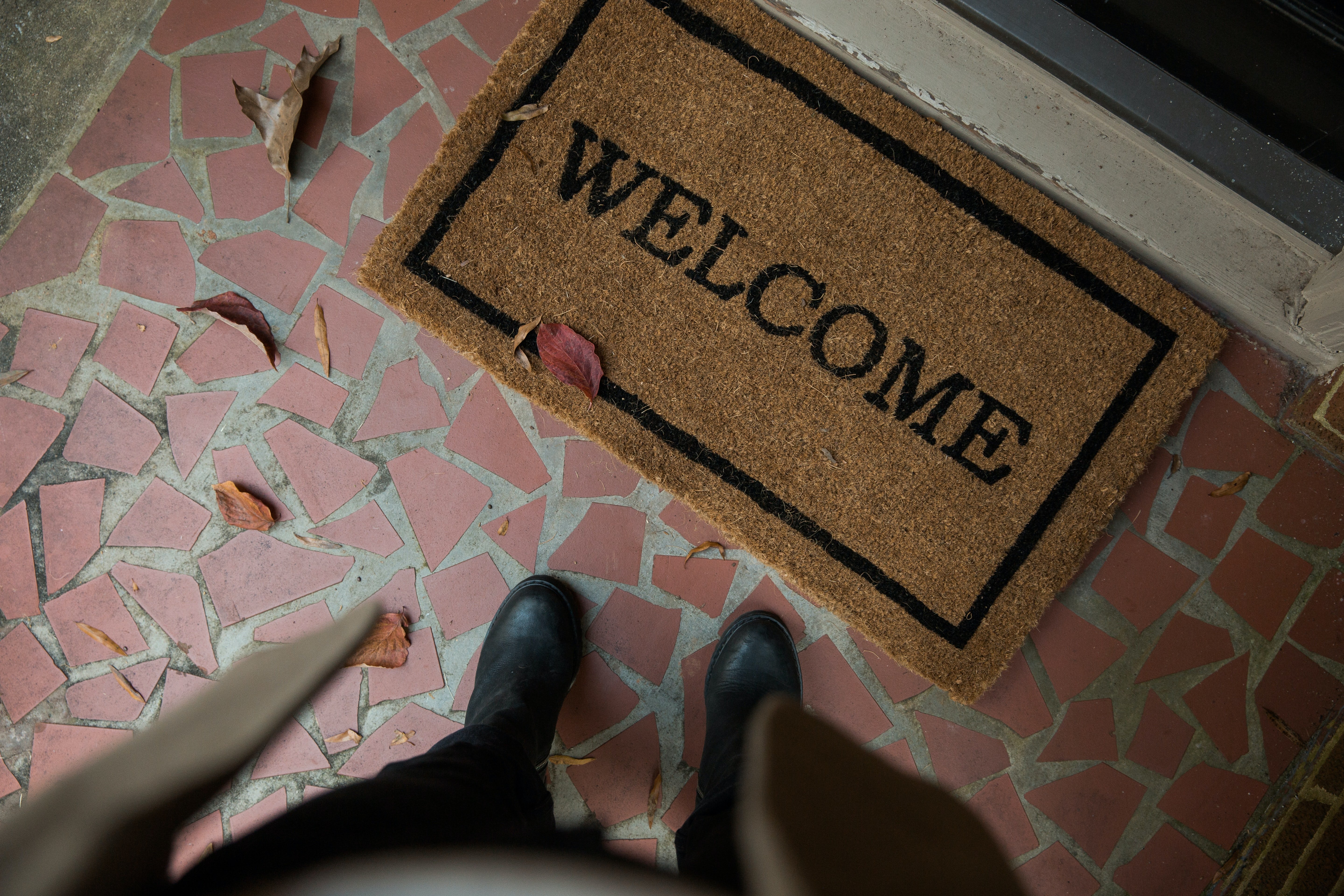 Mujer parada frente a una puerta con una alfombra de bienvenida. | Foto: Unsplash