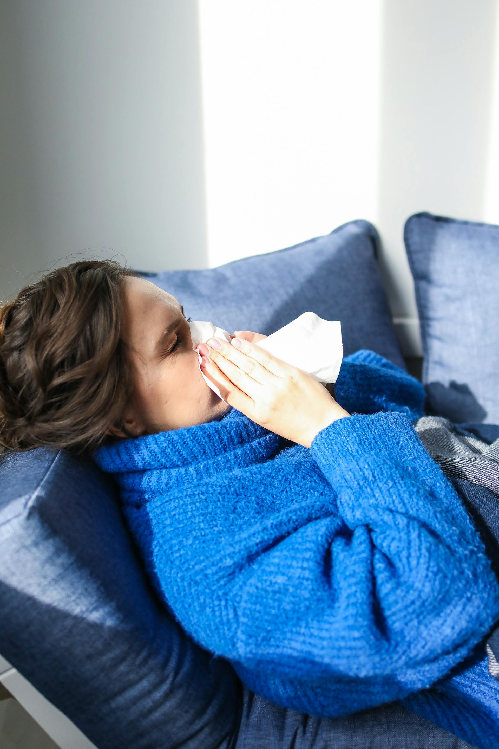 Una mujer enferma tumbada en un sofá | Fuente: Pexels