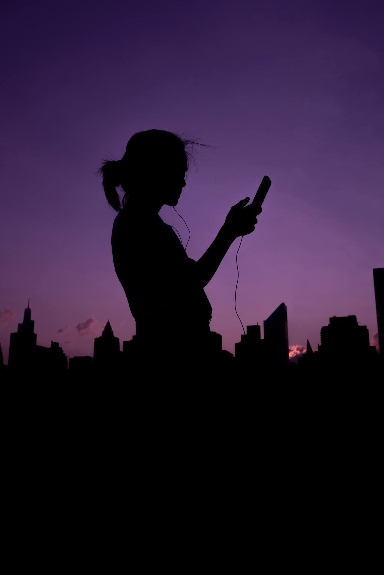 Silueta de una mujer sujetando su teléfono | Fuente: Pexels