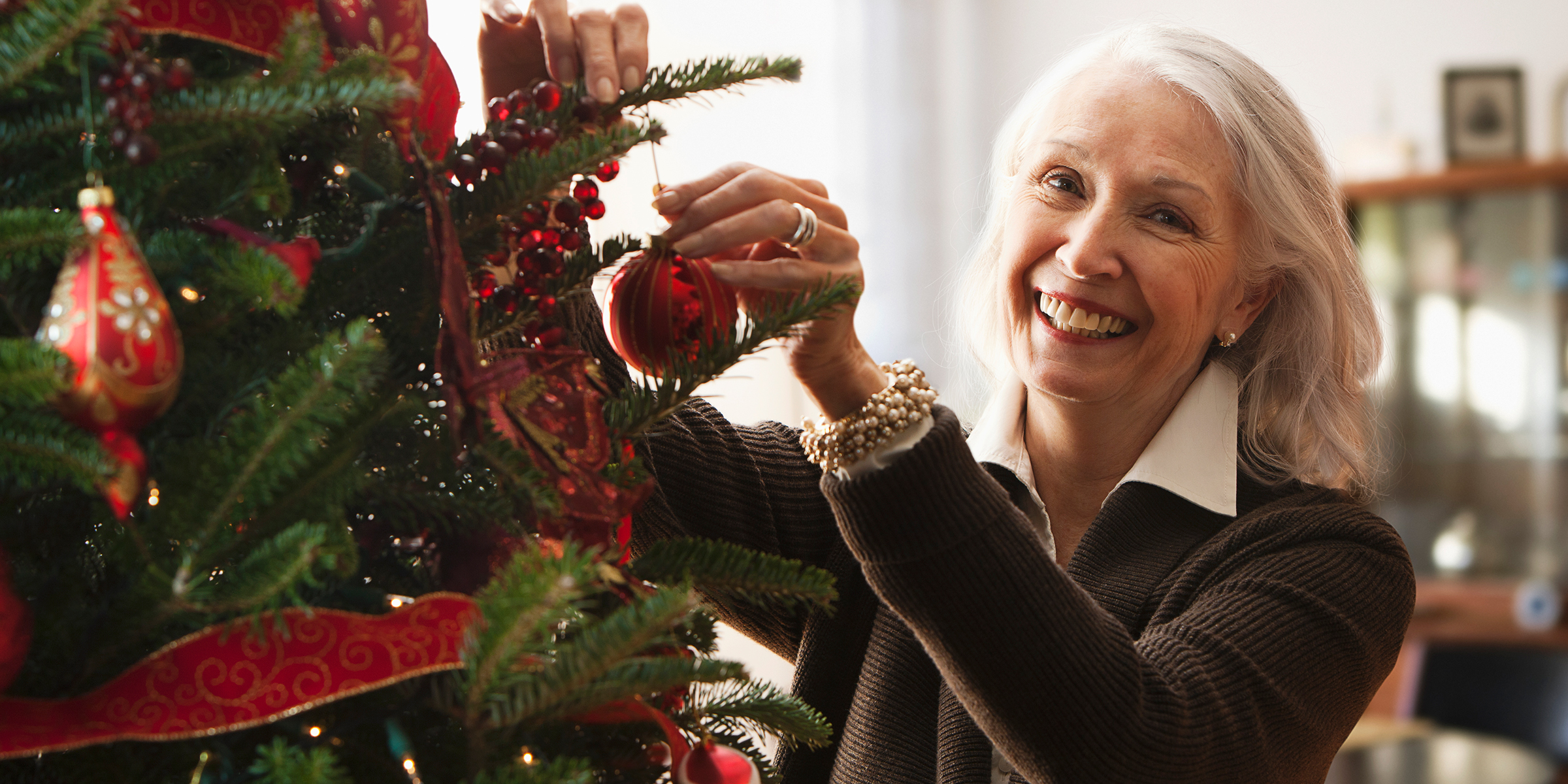 Una mujer decorando un árbol de Navidad | Foto: Getty Images
