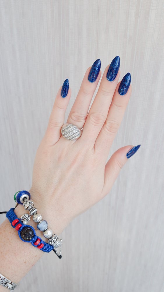 Mano femenina con uñas largas y manicura azul marino. | Foto: Shutterstock