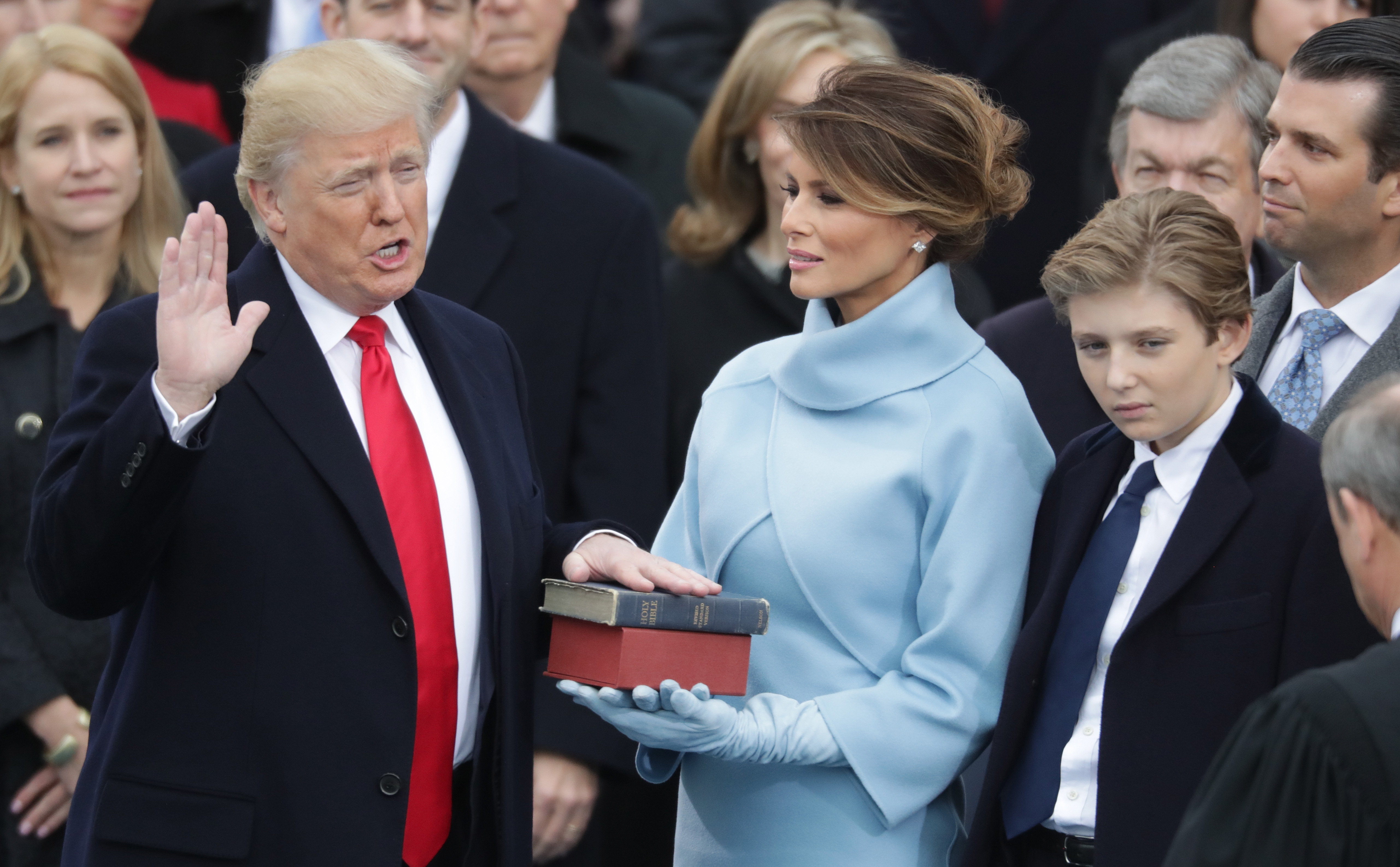 Donald Trump jura el cargo mientras Melania Trump sostiene la biblia y Barron Trump observa, en la fachada oeste del Capitolio de EEUU en Washington, DC, el 20 de enero de 2017 | Fuente: Getty Images