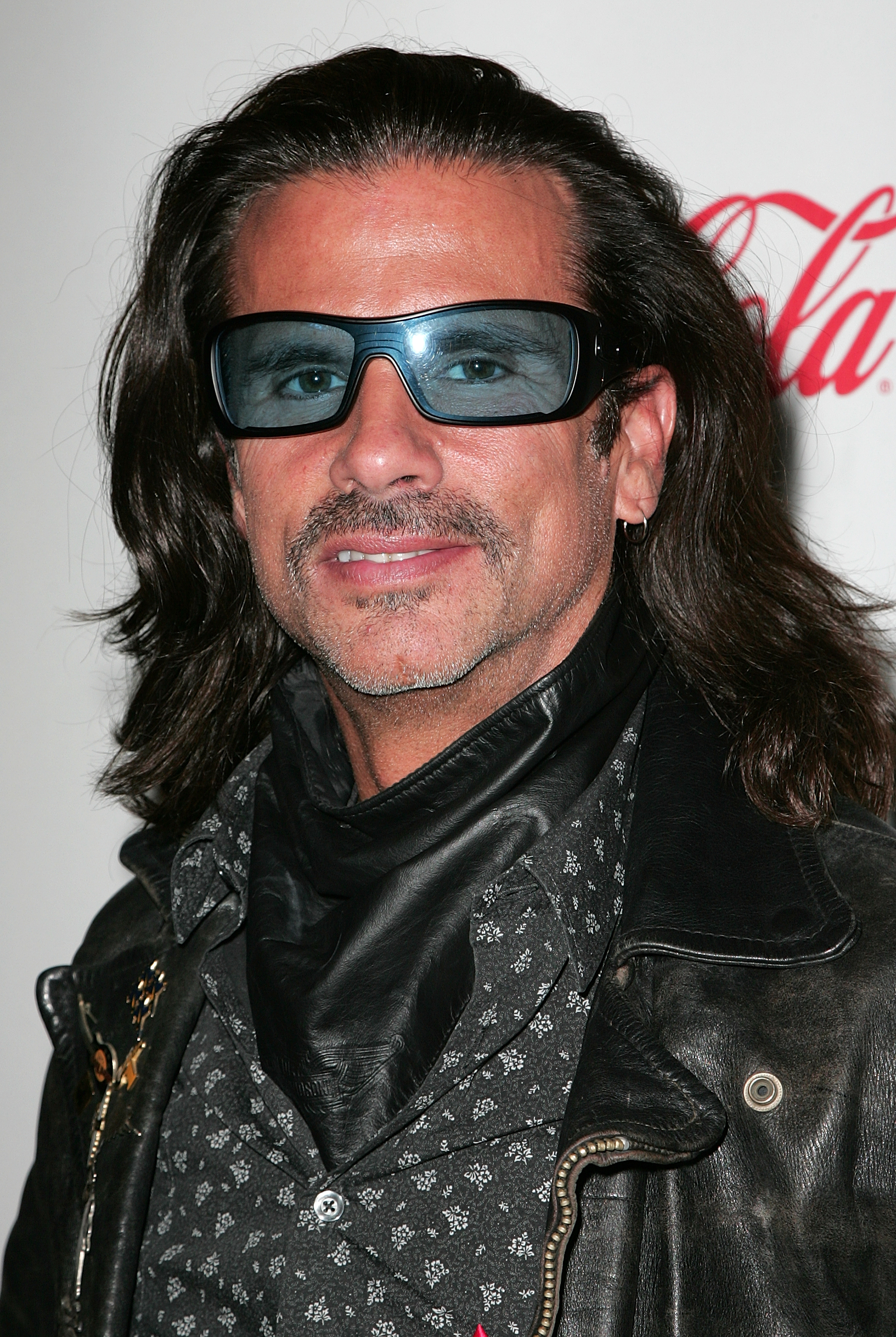 Lorenzo Lamas aporta un toque motero muy marcado al Desfile Navideño de Hollywood de 2009, celebrado en el Hotel Roosevelt de Hollywood, California, el 29 de noviembre de 2009. Con una sonrisa discreta y la barba bien recortada, el actor complementa su característica melena oscura hasta los hombros con unos lentes de sol envolventes de tonos azules, un cubrecuello de cuero oscuro, una camisa estampada abotonada y una chaqueta de cuero desgastada. | Fuente: Getty Images