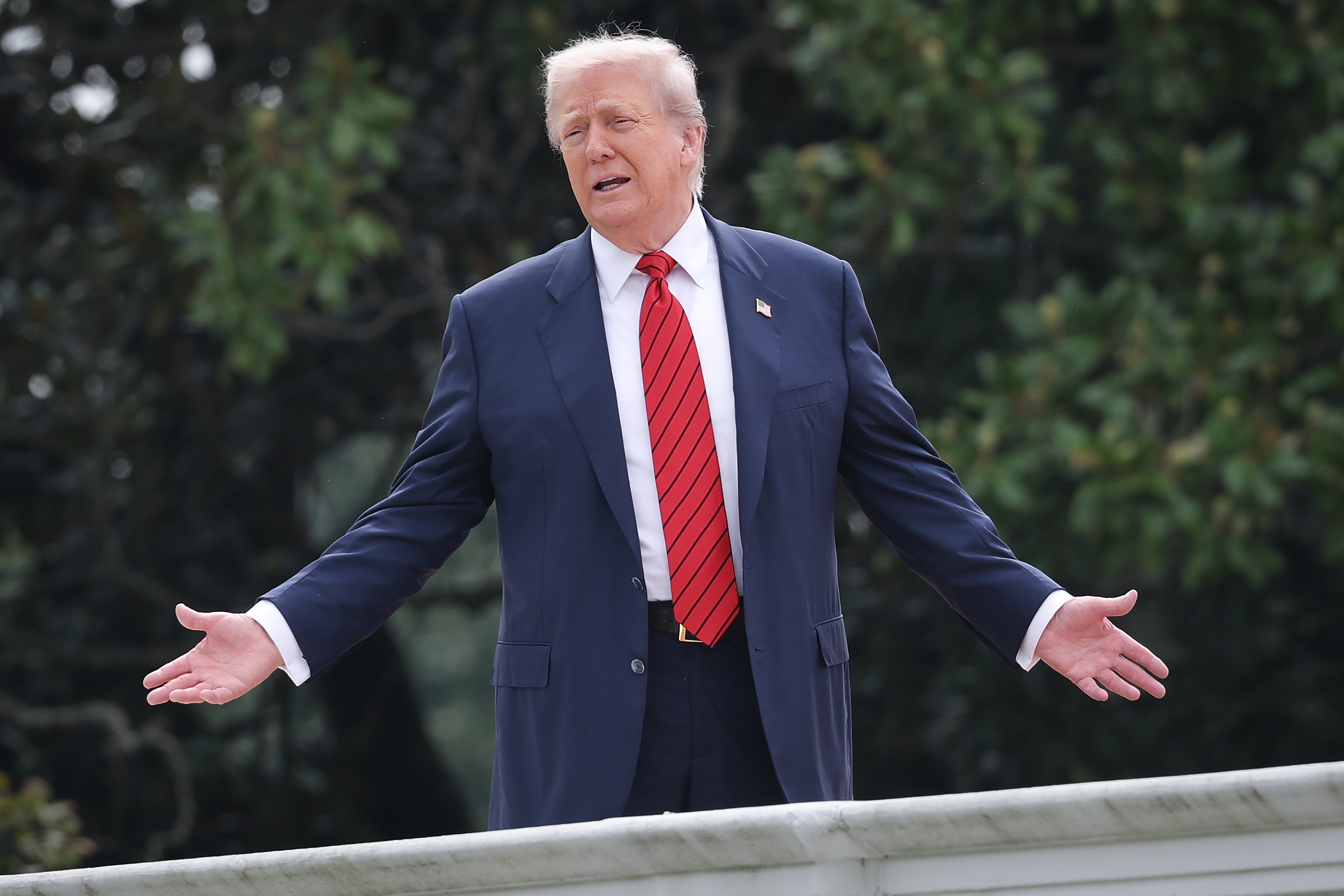 Durante un raro paseo por la azotea del ala oeste de la Casa Blanca, el presidente Donald Trump extiende los brazos mientras responde a los periodistas, convirtiendo el momento en un espectáculo.