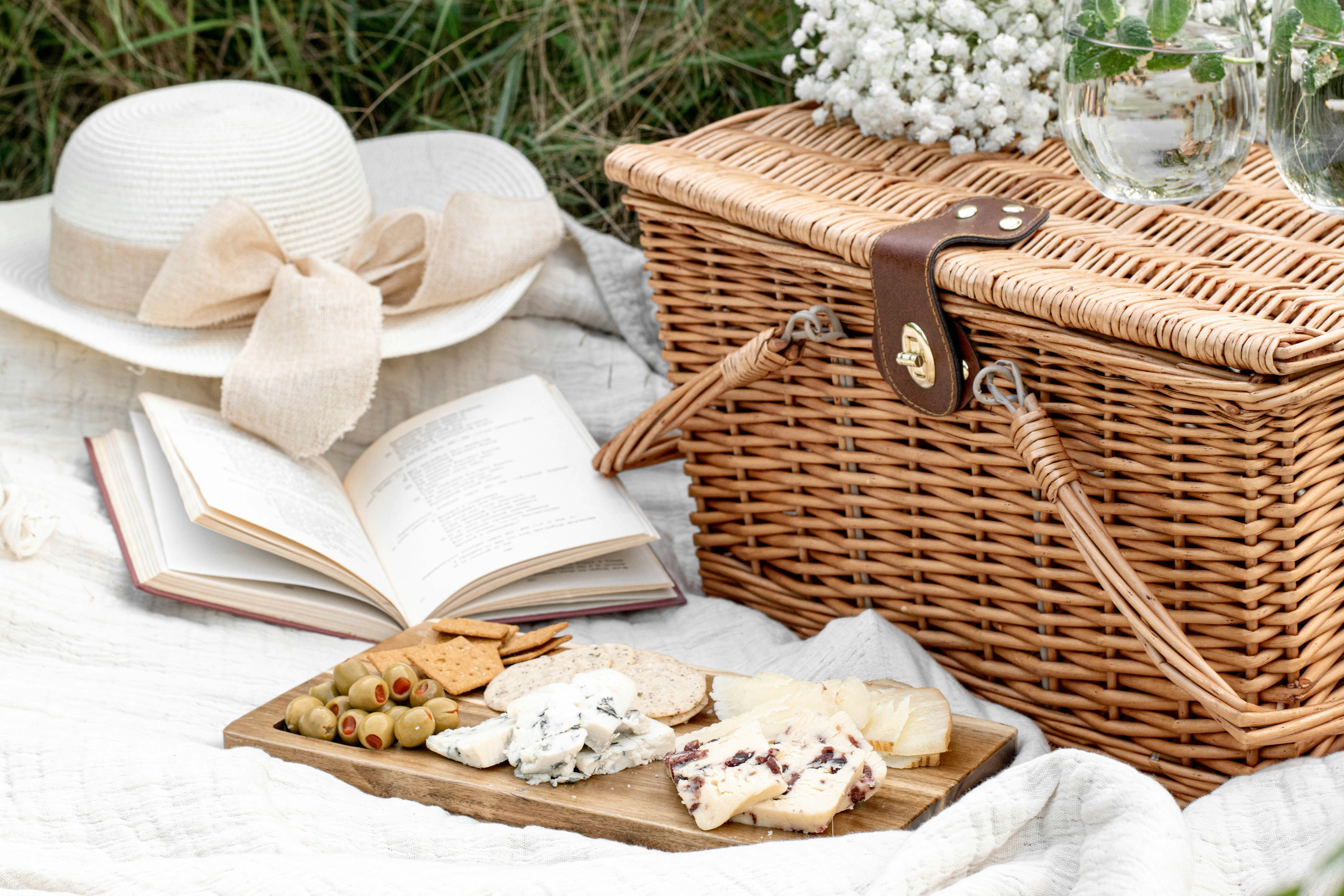 Una cesta de picnic, comida, un libro y un sombrero | Fuente: Unsplash