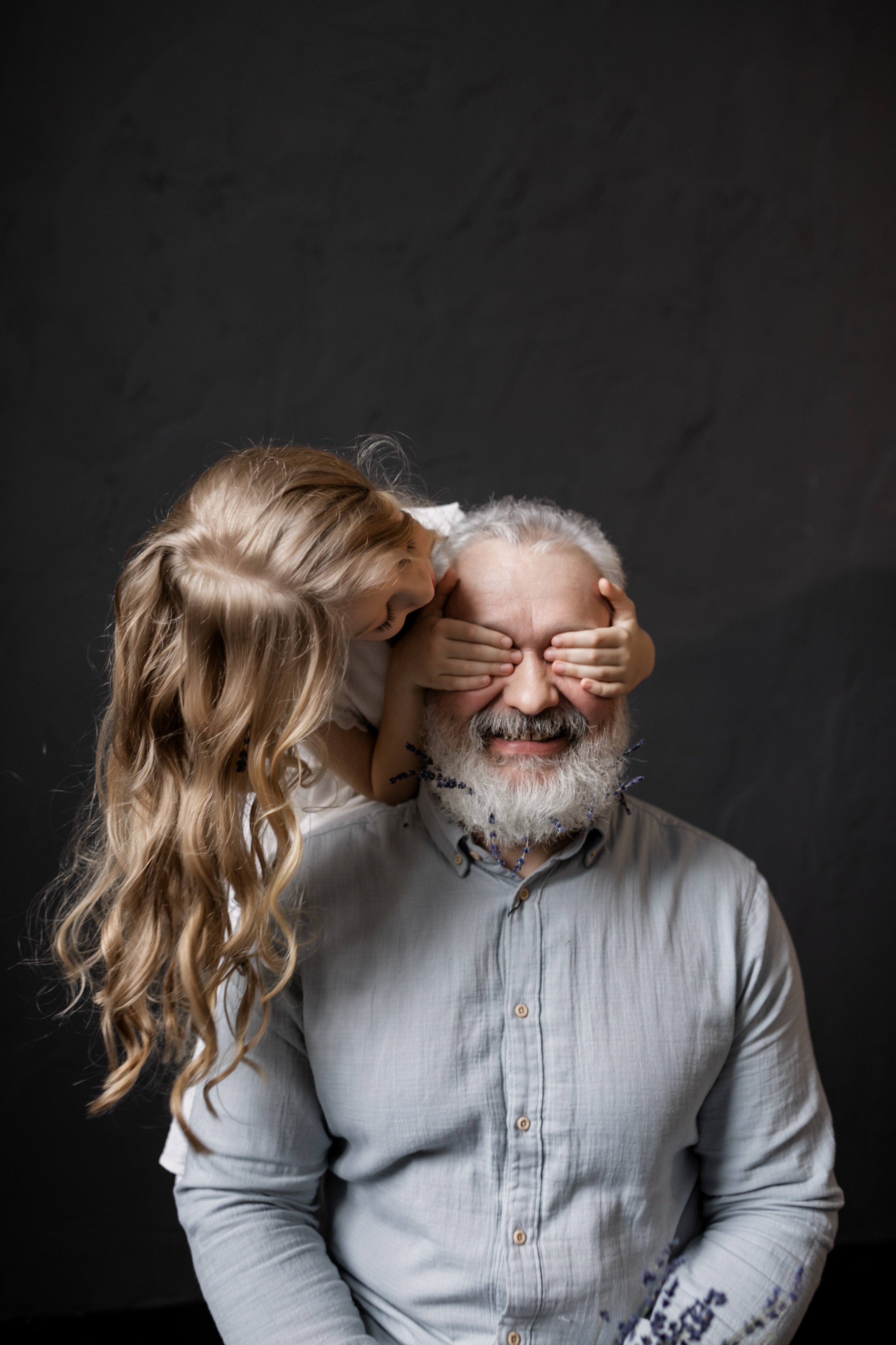 Una nila tapa los ojos a un hombre mayor. | Foto: Pexels