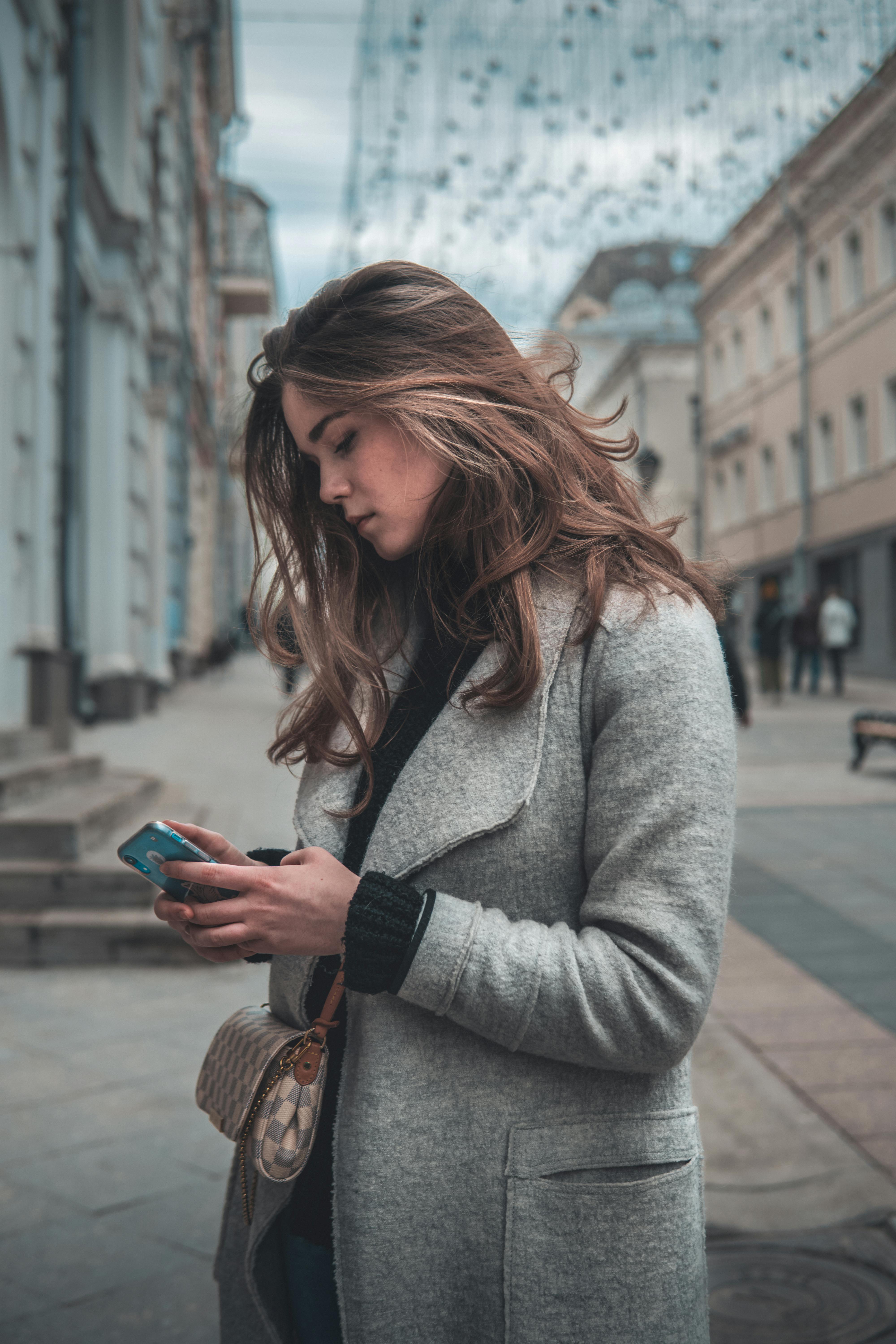 Una mujer en la calle usando su teléfono | Fuente: Pexels