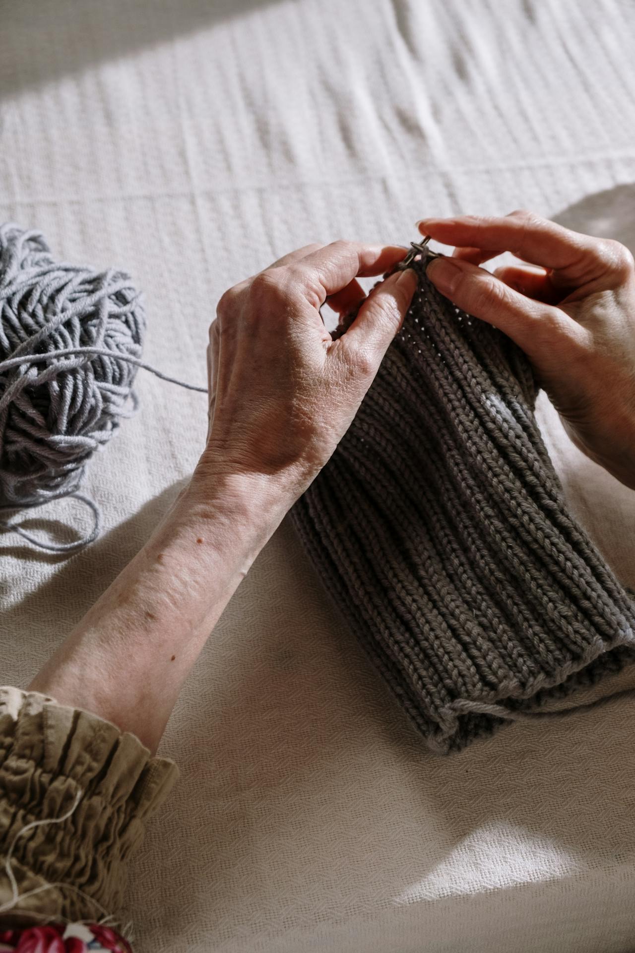Primer plano de una mujer mayor tejiendo un hilo gris | Fuente: Pexels