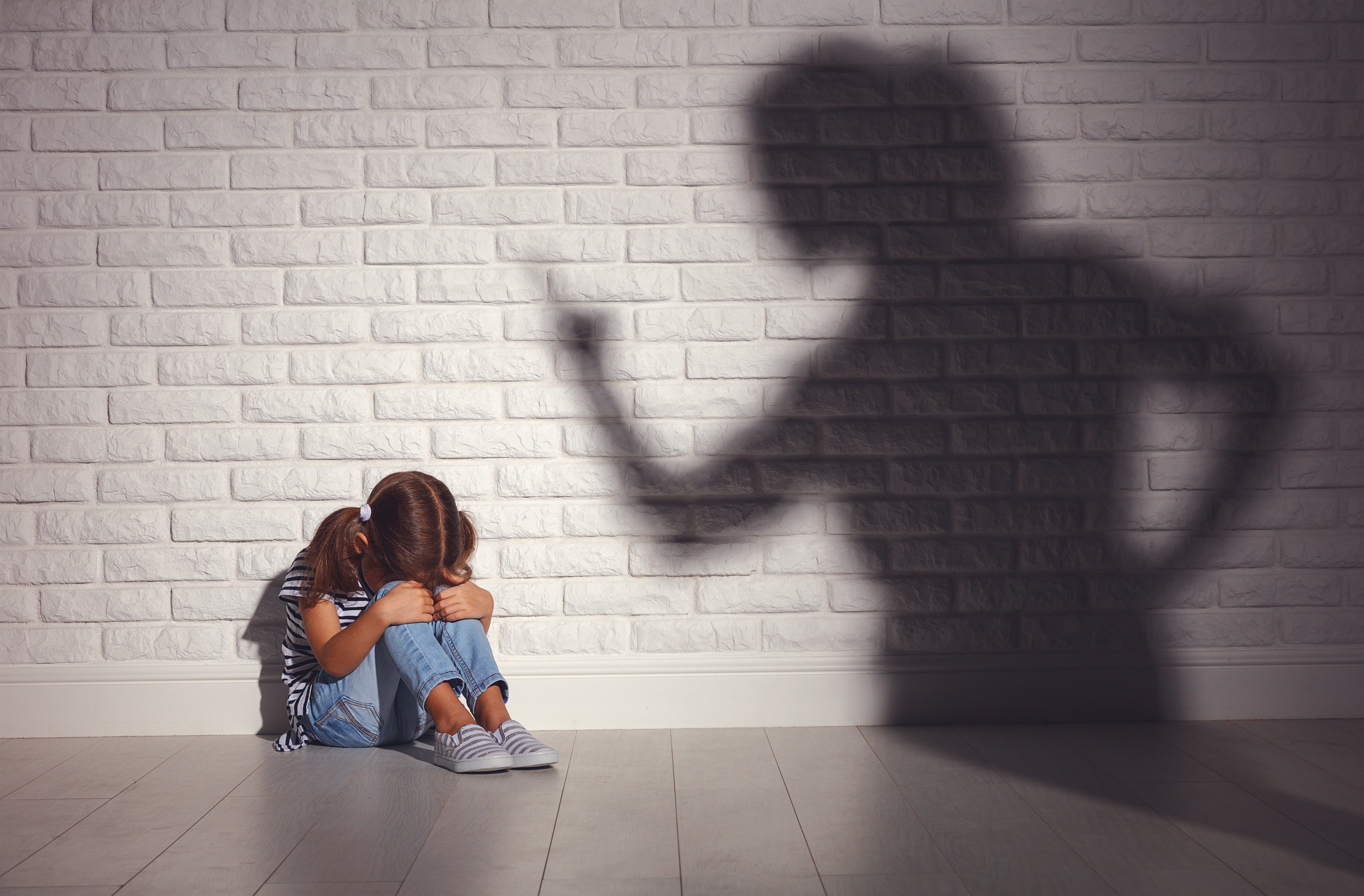 Niña triste y sombra de madre molesta. | Foto: Shutterstock