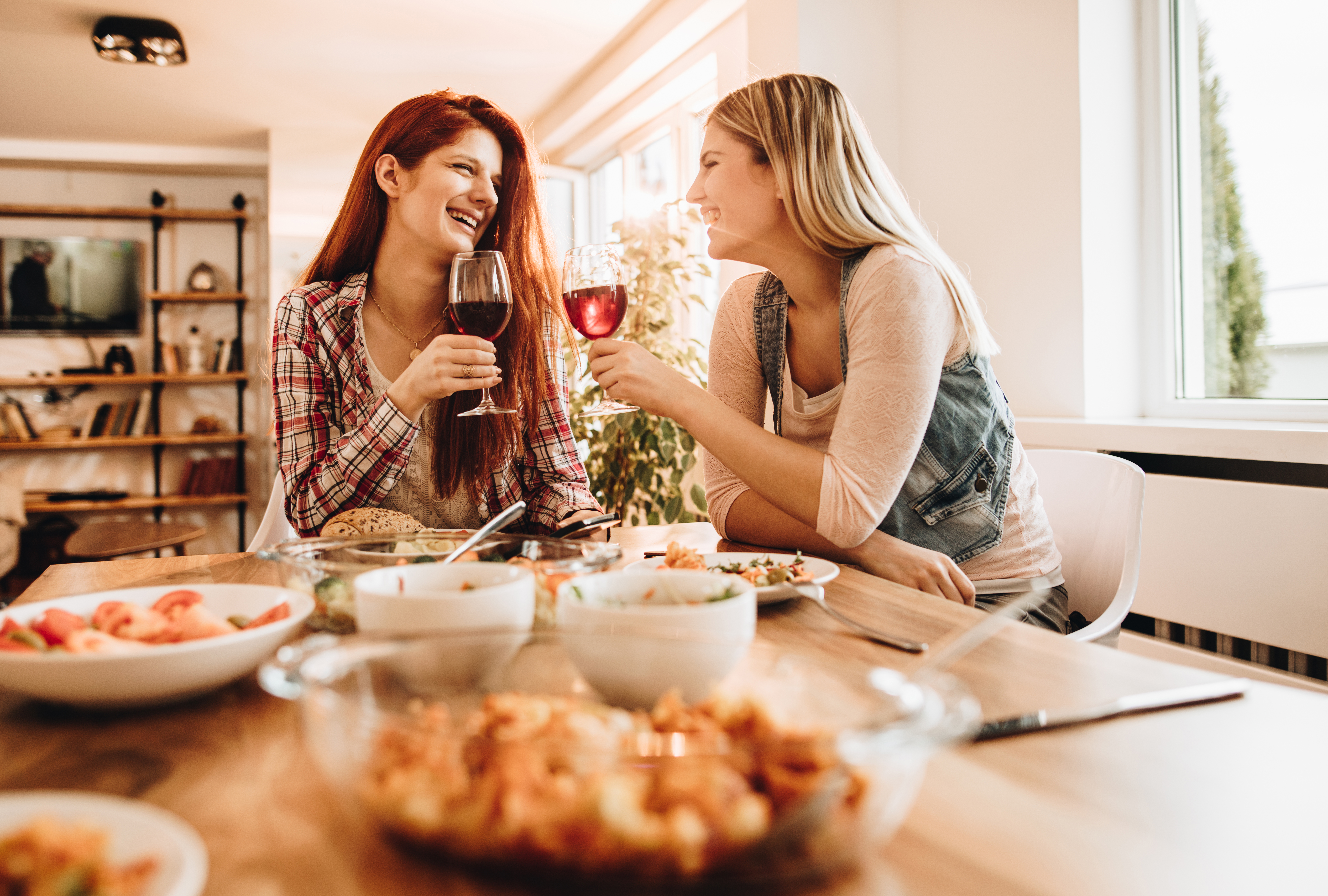 Mujeres jóvenes y felices hablando y bebiendo vino durante el almuerzo | Foto: Getty Images