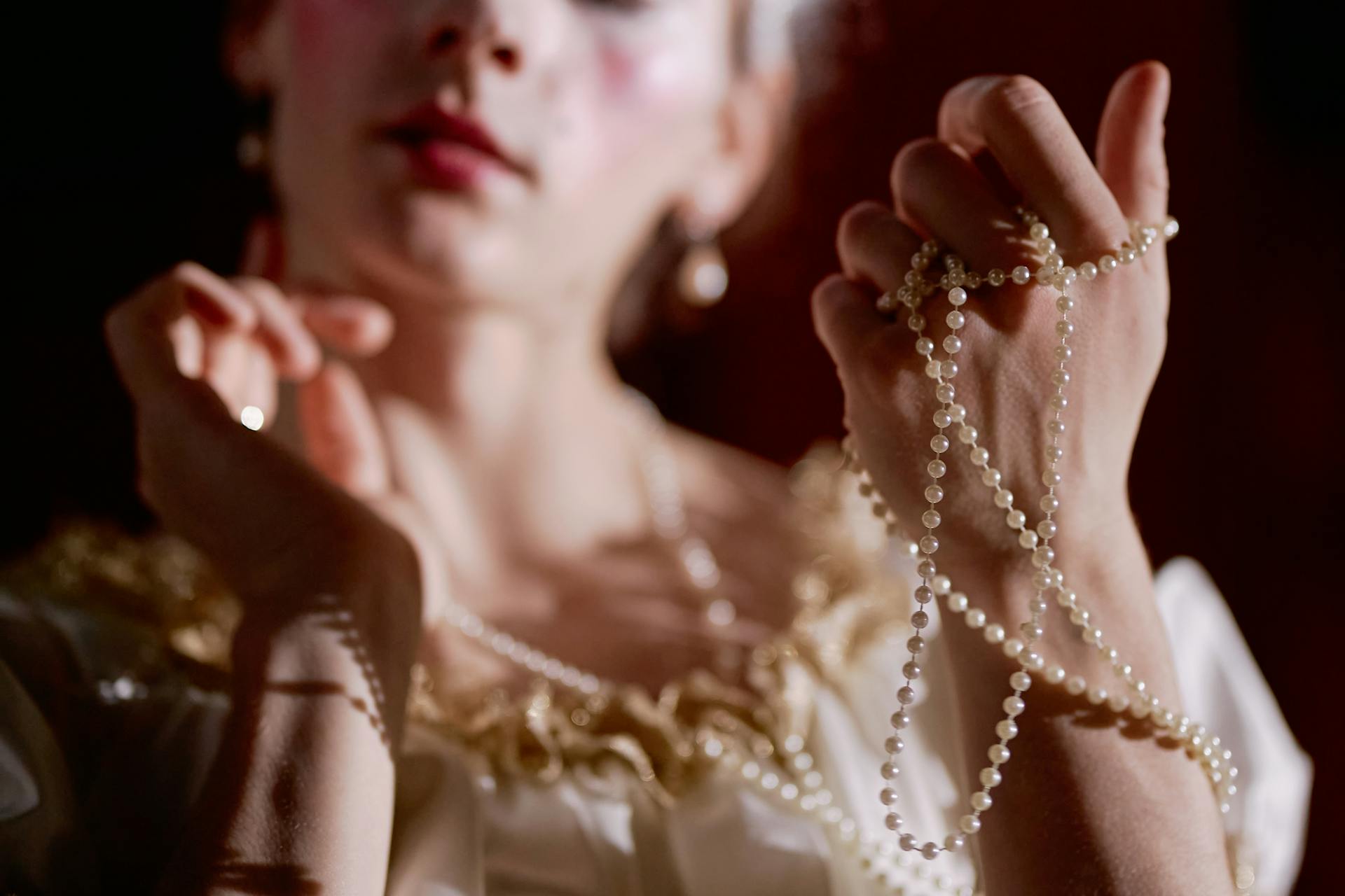 Una mujer adinerada jugueteando con hilos de perlas | Fuente: Pexels