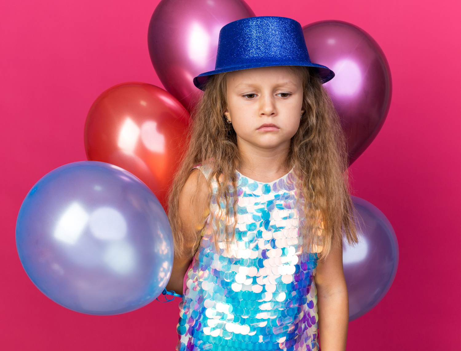 Una niña triste sujetando globos de colores | Fuente: Freepik