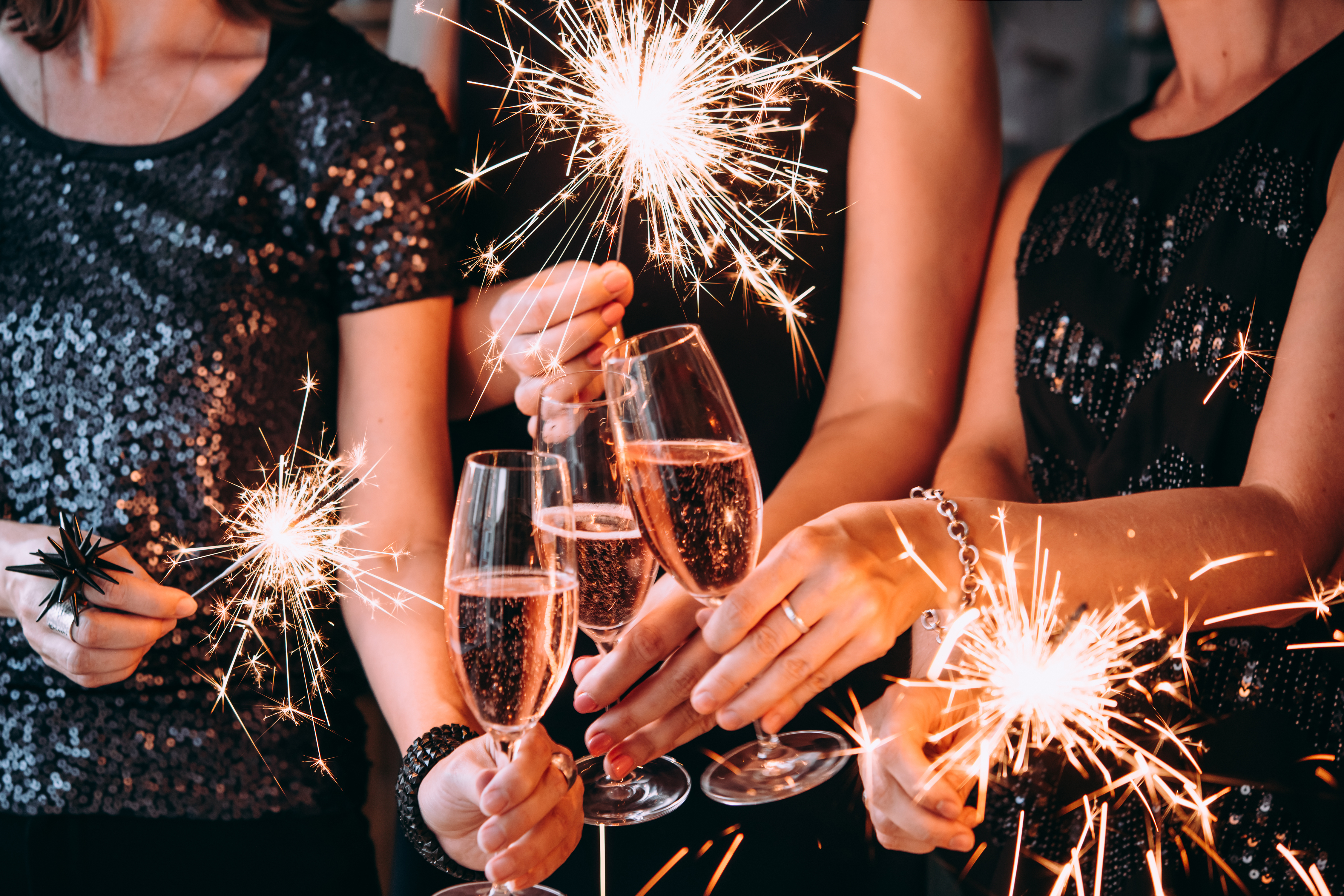 Un grupo de amigos celebrando el año nuevo con luces de Bengala y champán rosado | Fuente: Shutterstock