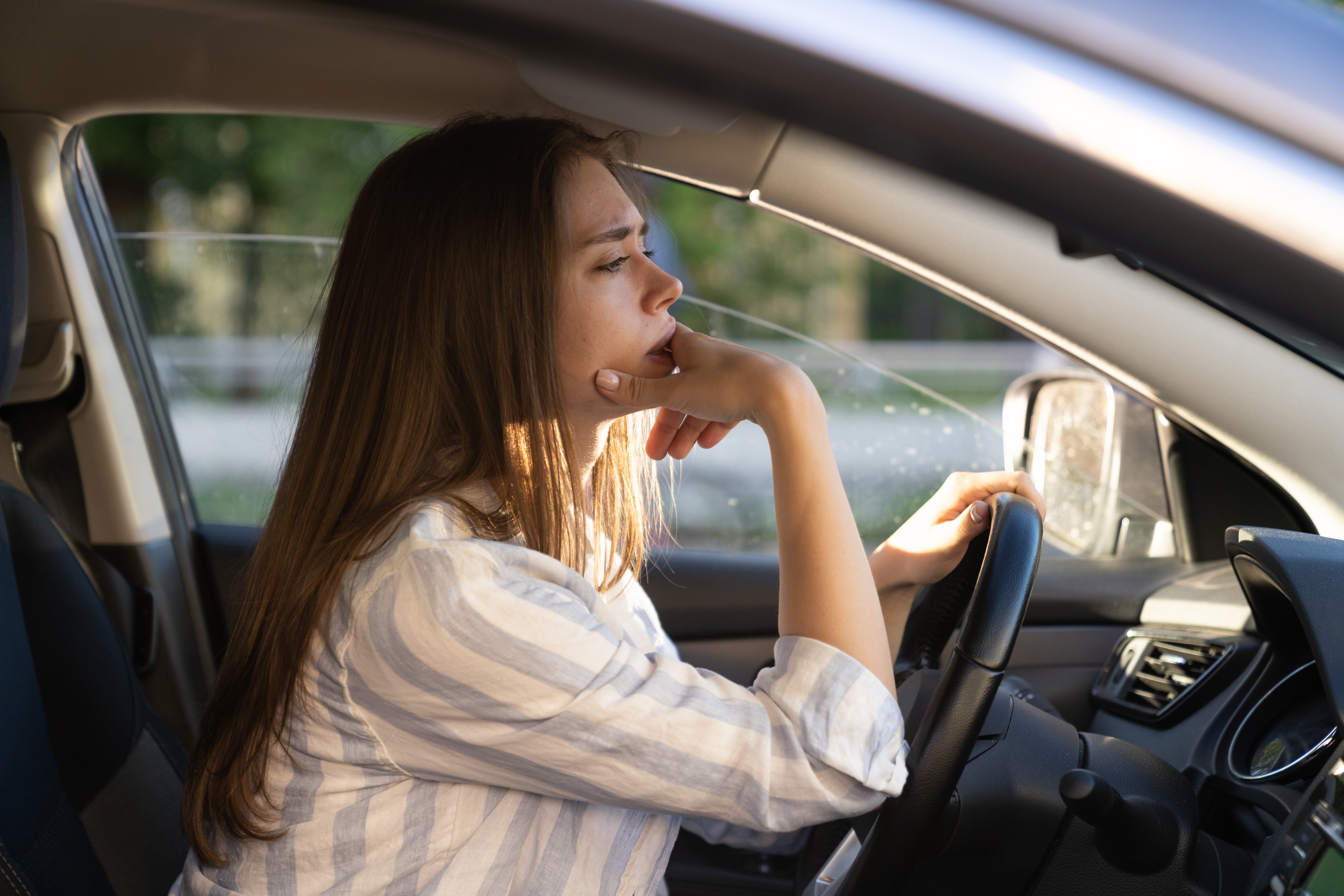 Una mujer perdida en sus pensamientos mientras conduce | Fuente: Shutterstock