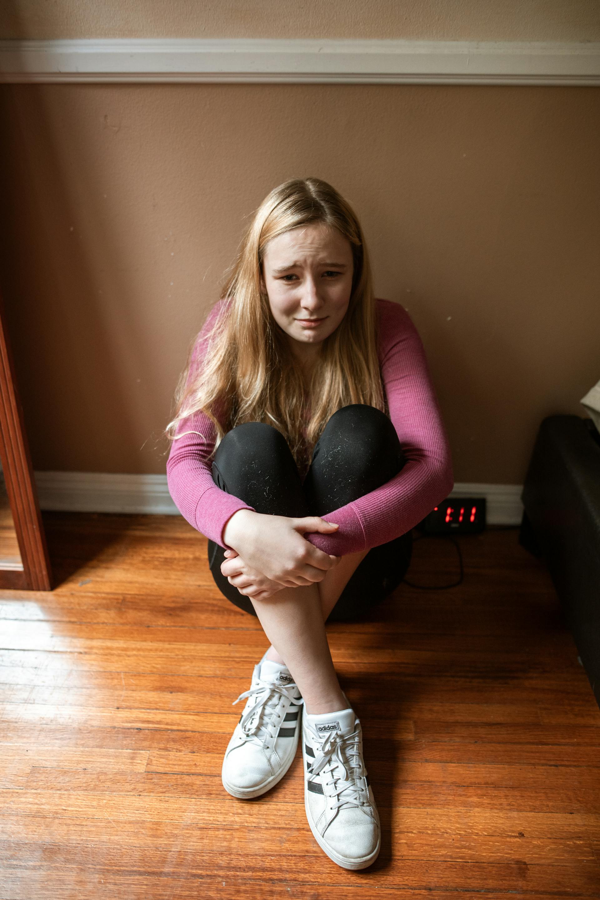 Una joven adolescente sentada en el suelo y llorando | Fuente: Pexels