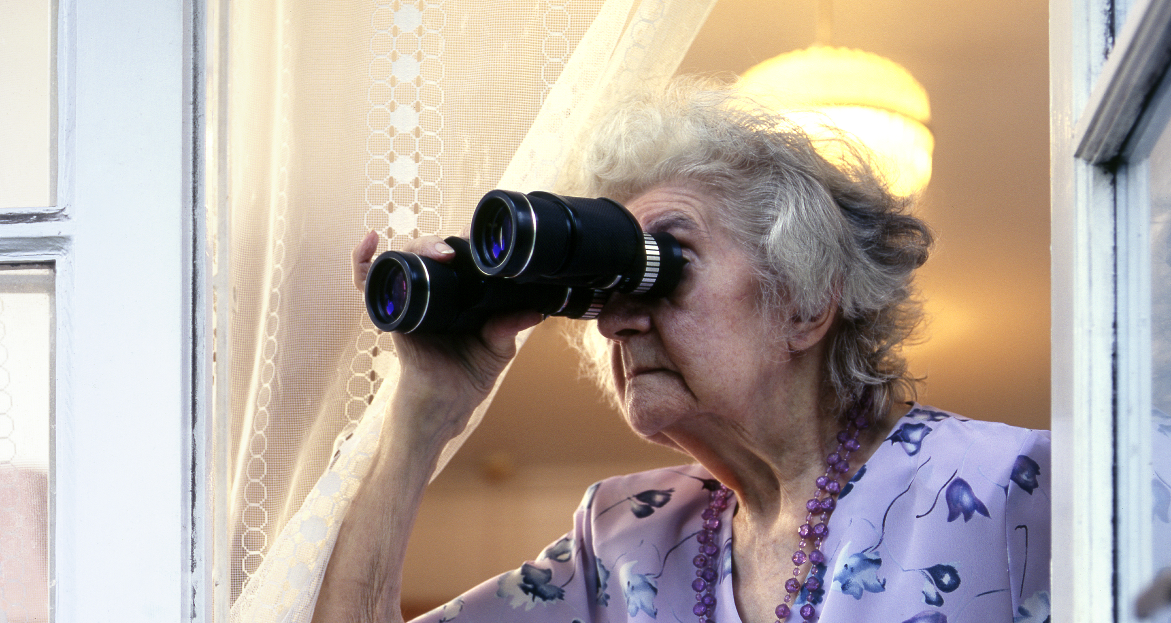 Una mujer mayor mirando a través de unos prismáticos | Foto: Getty Images