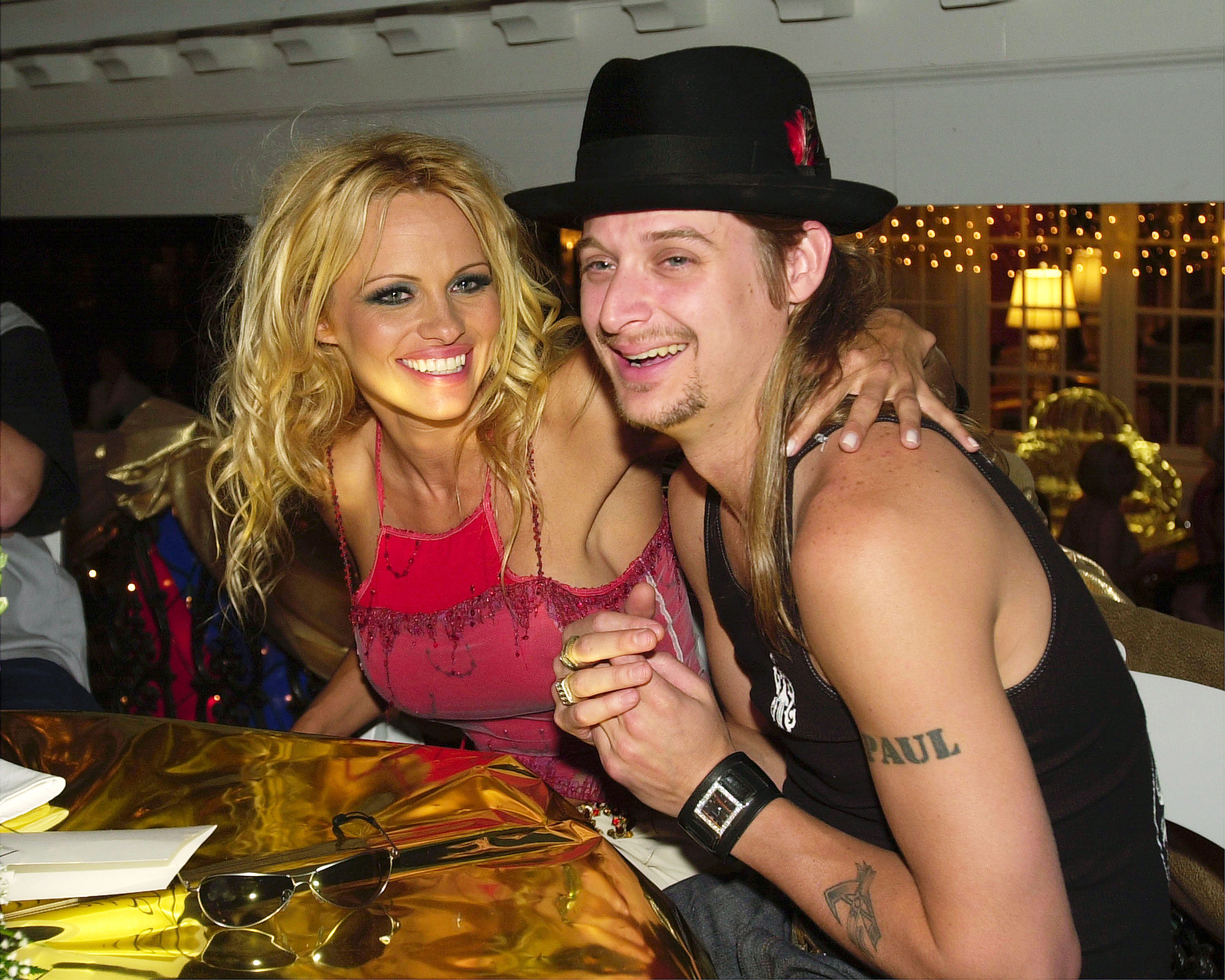 Pamela Anderson y el músico Kid Rock se echan unas risas mientras se acomodan en sus asientos en la gala Barnstable-Brown Derby Eve, celebrada en Louisville, Kentucky, el 4 de mayo de 2001. Vestida con un top magenta bordado y con las gafas de sol apoyadas en la mesa dorada, Anderson rodea con un brazo a Rock, capturando todo el protagonismo de sus relaciones de principios de la década de 2000 antes de cambiar los espectáculos de la alfombra roja por el tranquilo refugio de Arcady. | Fuente: Getty Images