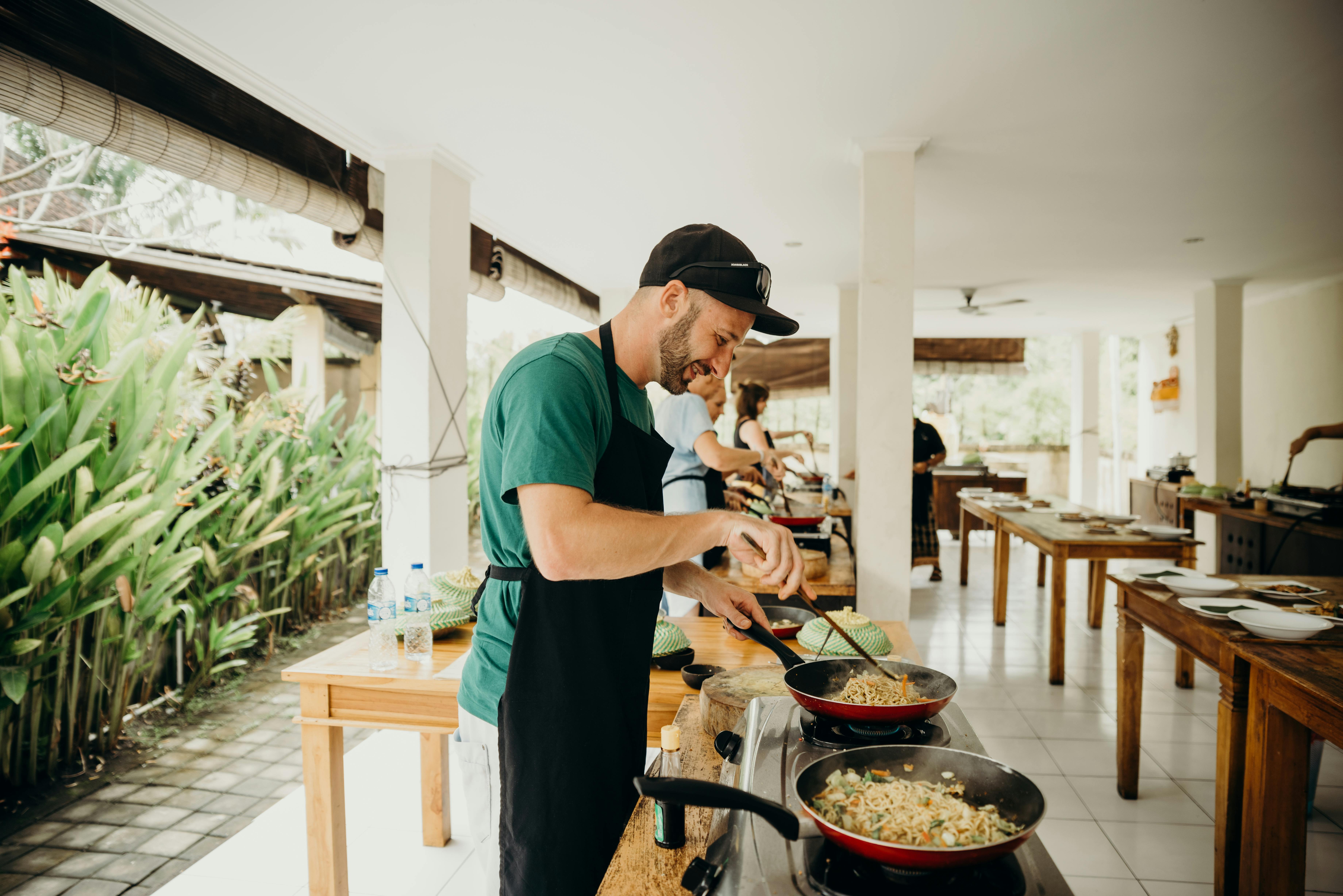 Un hombre con delantal negro cocinando alimentos en un concurso de cocina | Foto: Pexels